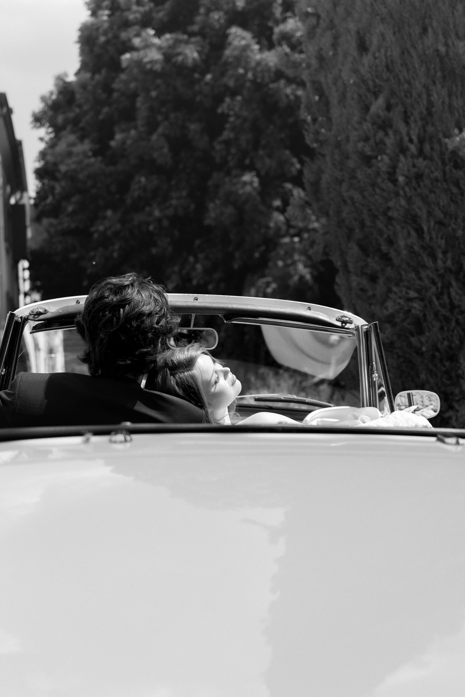A black and white photo sequence showing someone reclining in a vintage convertible car on a sunny day.