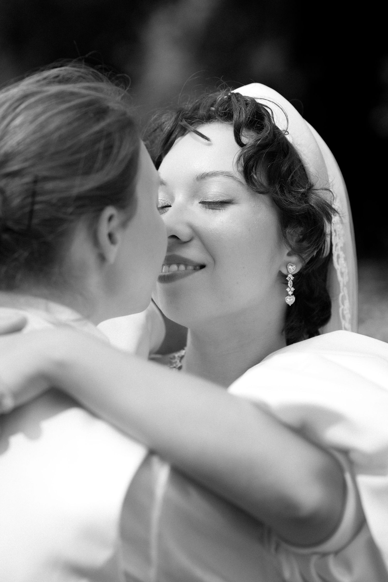 Black and white photo of two brides embracing and sharing a tender moment on their wedding day.