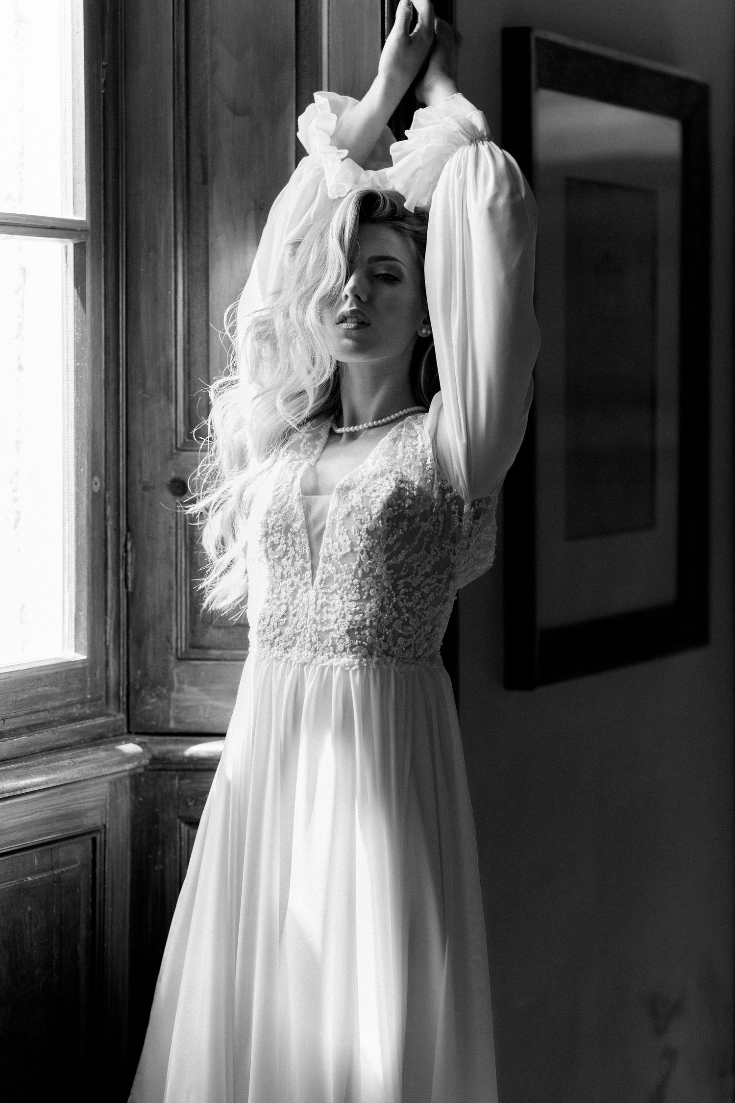 A series of four black and white photos showing a person in a flowing white vintage-style dress posing near a window. Wedding Verona