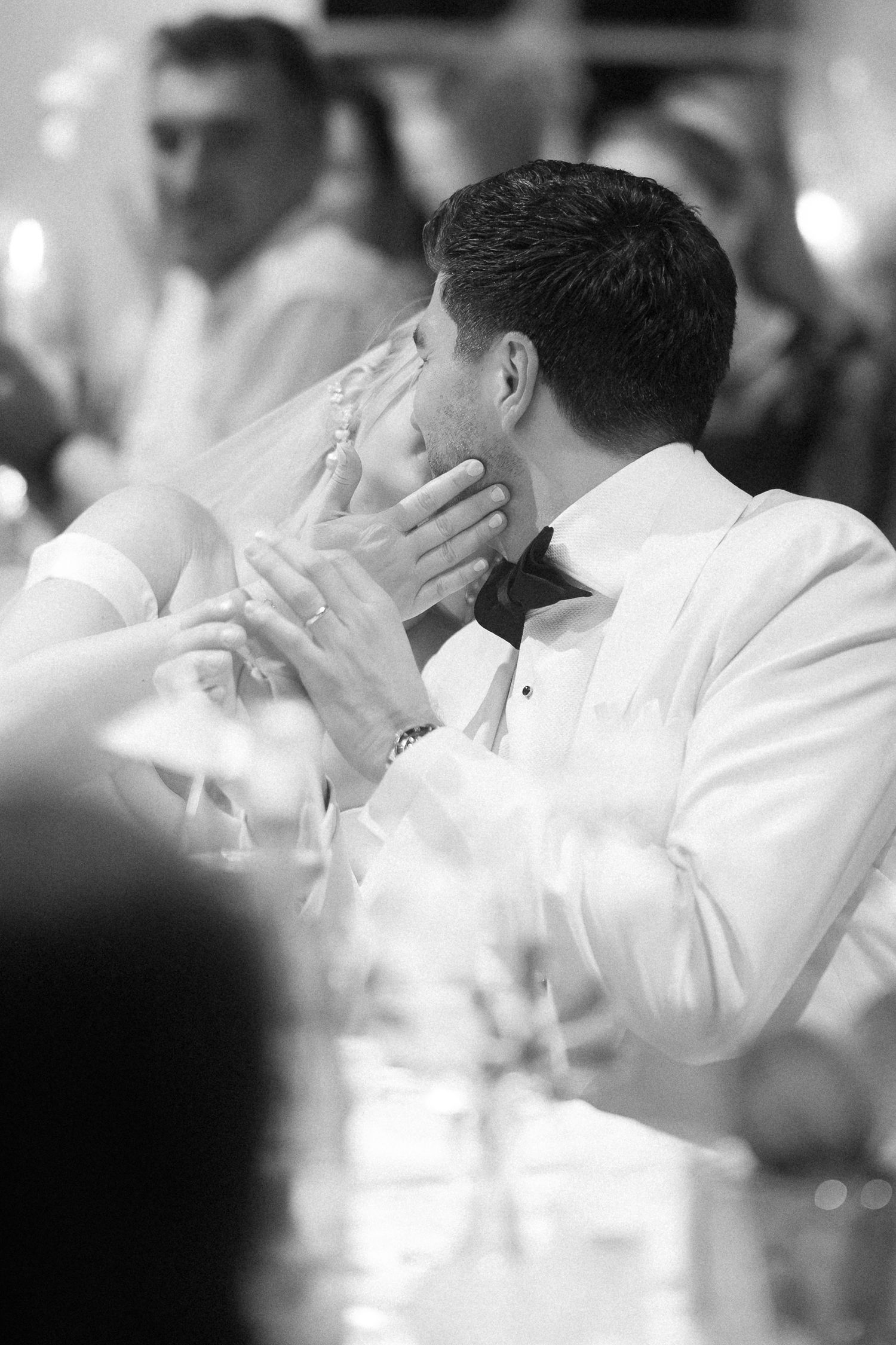 A group of people in white attire cover their faces with their hands during what appears to be an emotional moment.