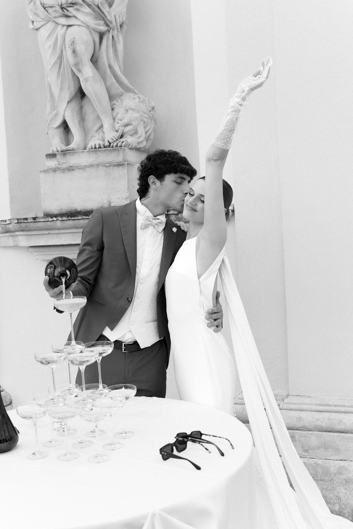 A black and white photograph shows a person photographing a scene through white fabric drapes in an artistic setting. Villa Mosconi Bertani