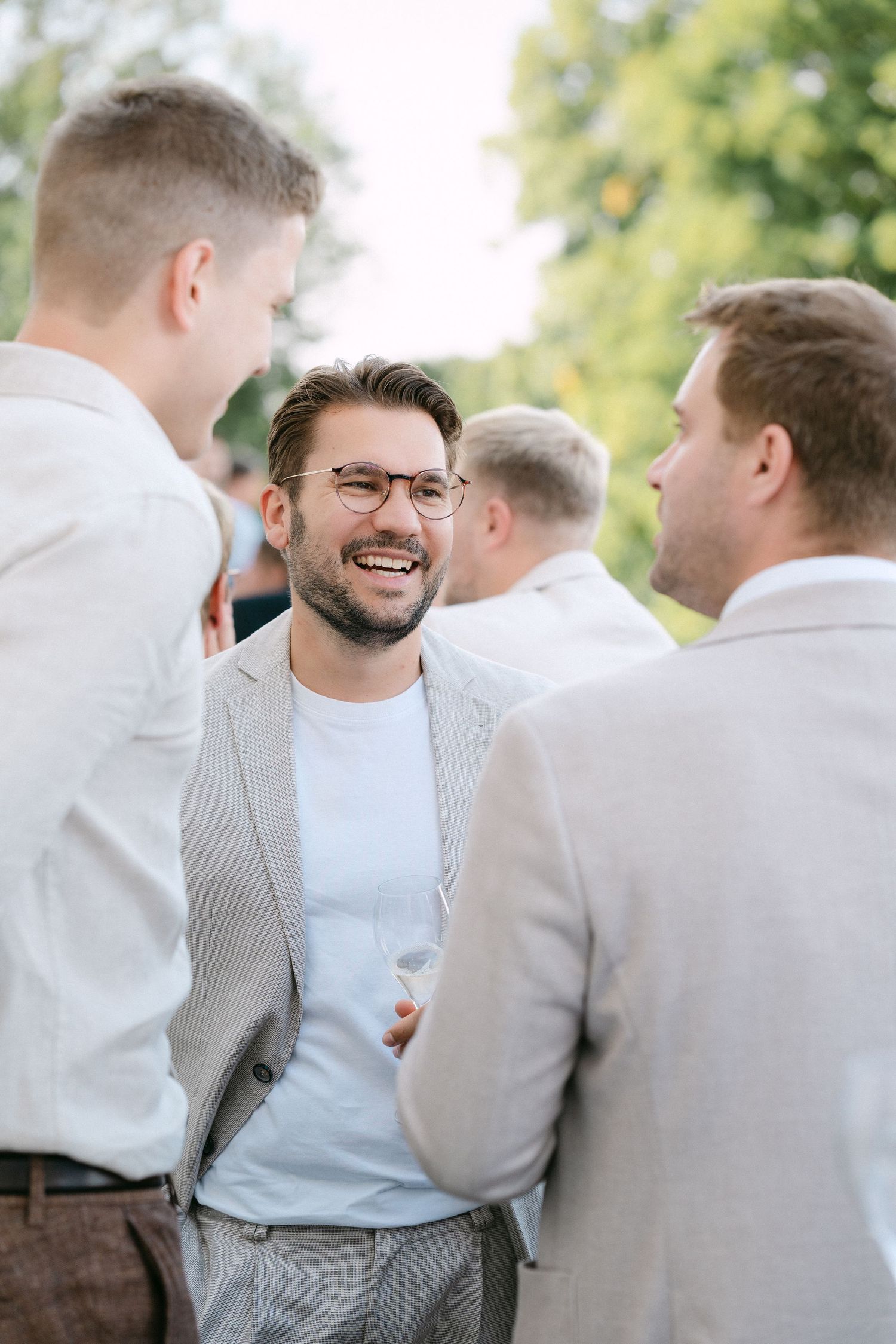 A group of friends in casual formal attire share a laugh during an outdoor gathering. Schloss Solitude