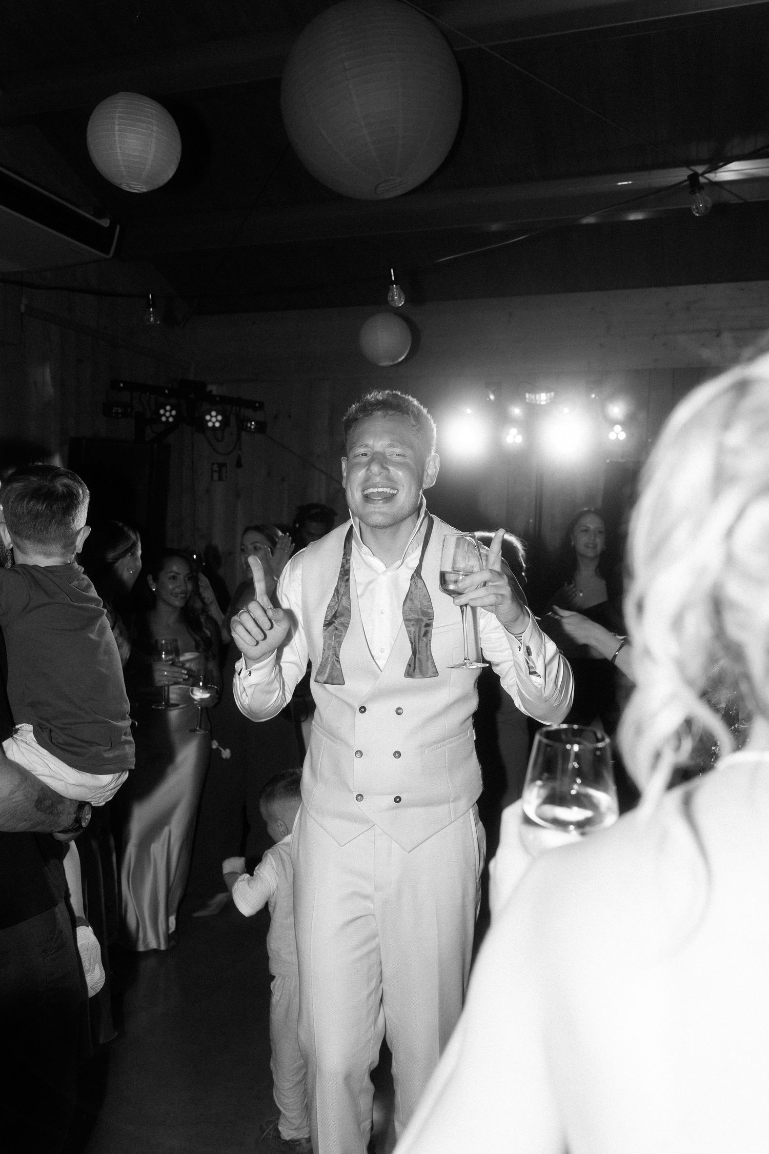 Wedding guests dance and celebrate on a dark dance floor during an evening reception party.
