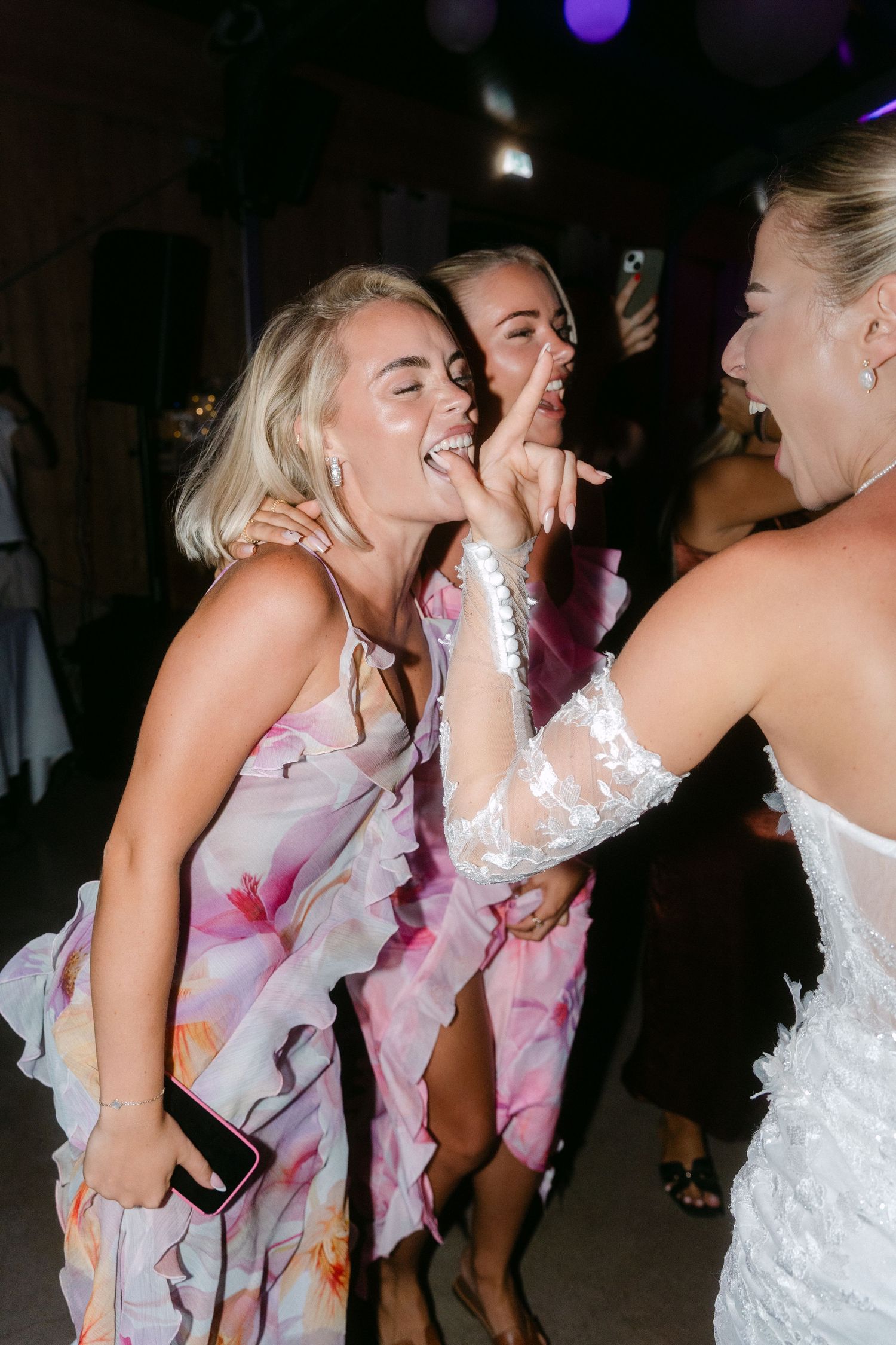 Wedding party dancing and celebrating at a dimly lit reception venue.