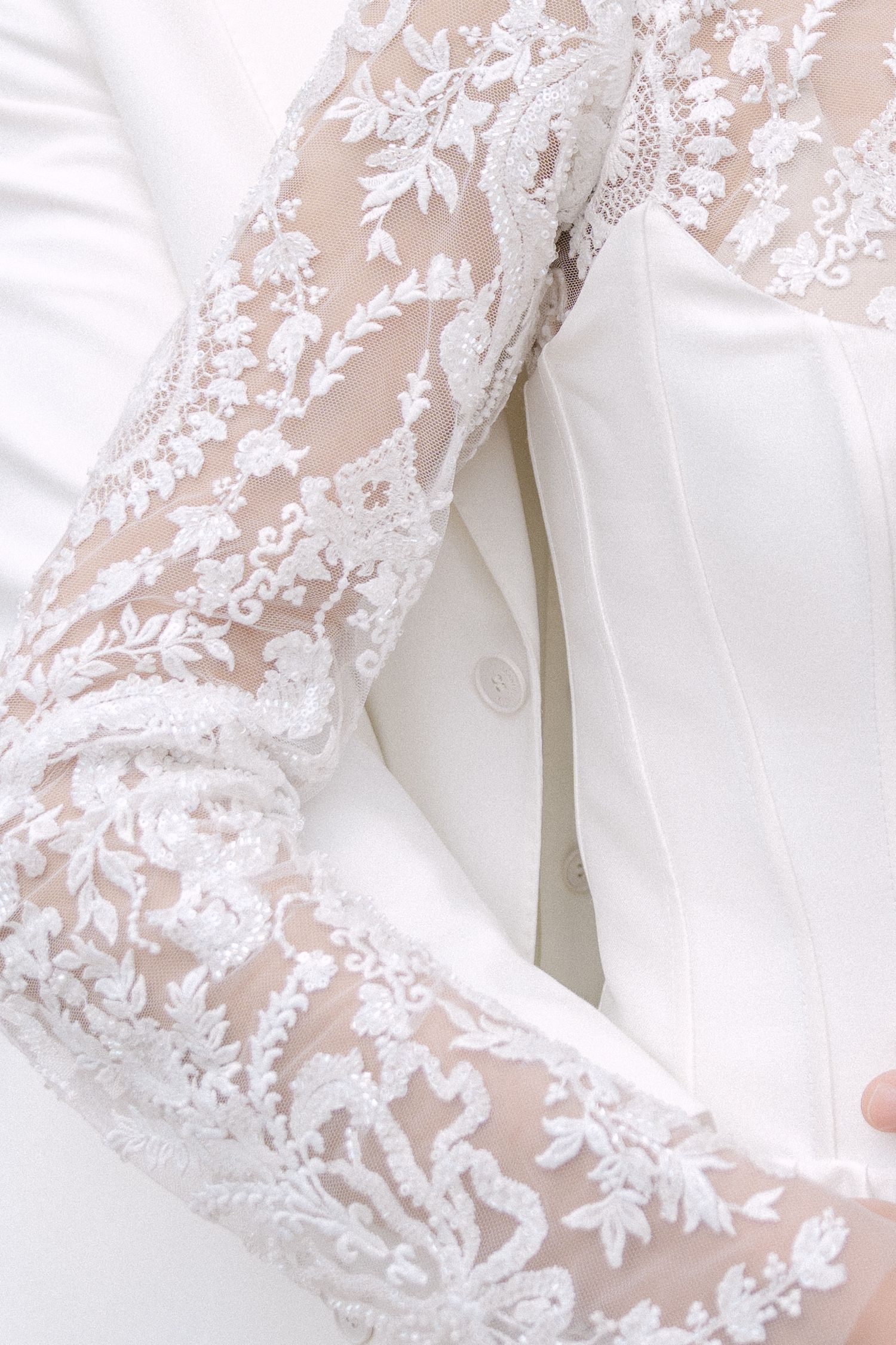 Close-up details of delicate white lace embroidery on sheer fabric with floral patterns and intricate needlework. Villa Mosconi Bertani