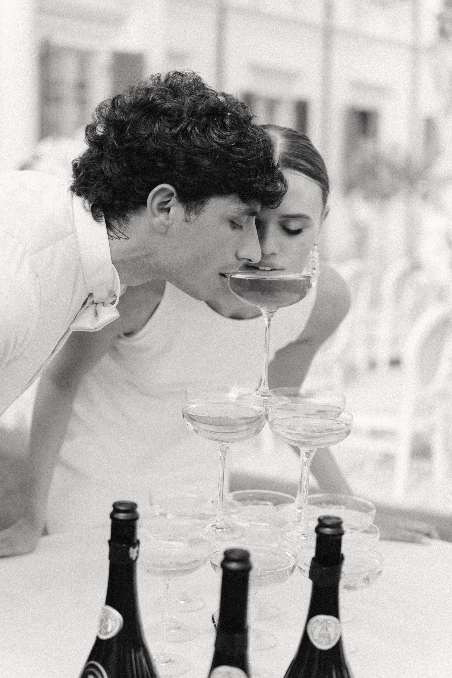 People lean in to admire a champagne tower being filled with bubbly at an elegant celebration. Villa Mosconi Bertani