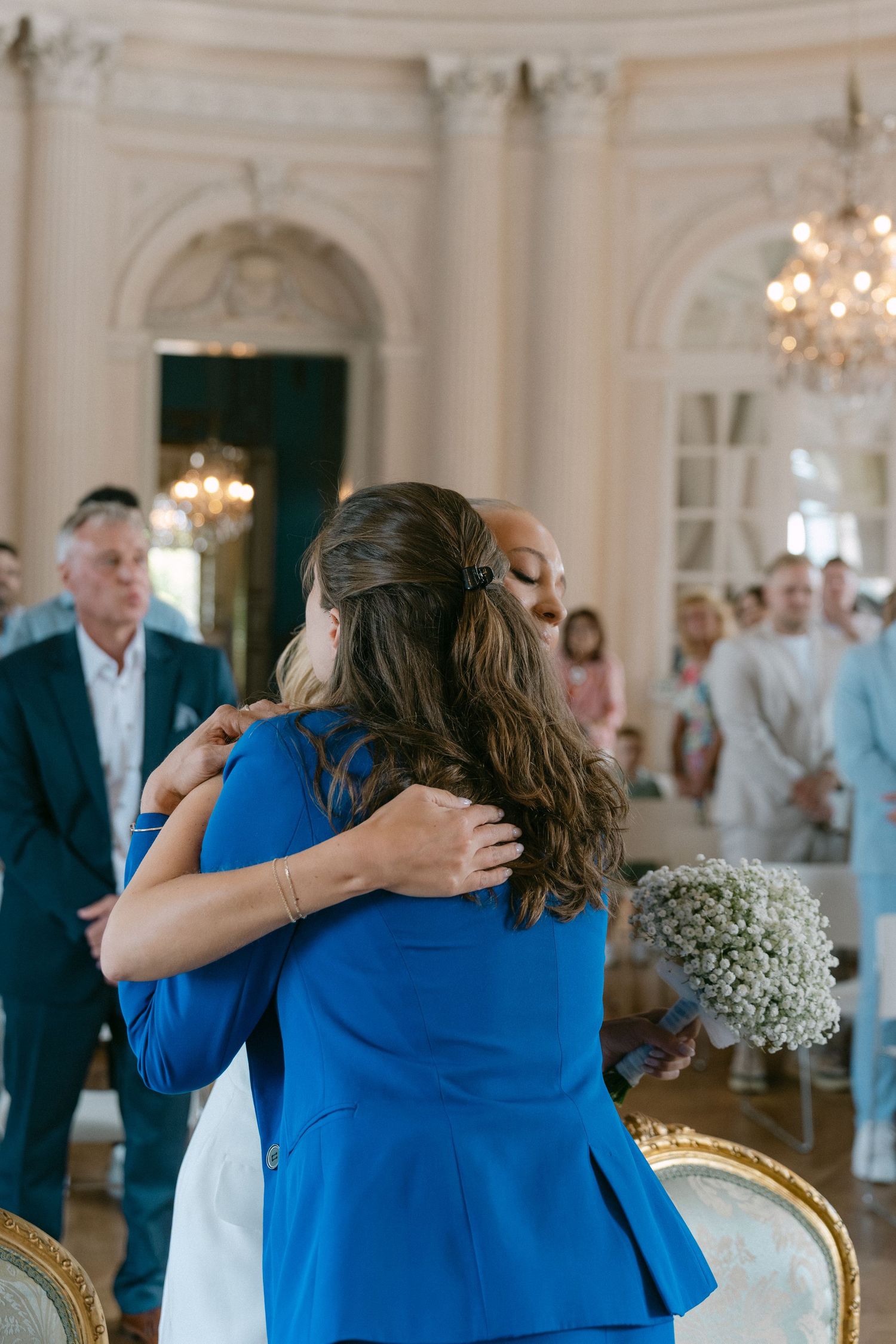 Sequence of photos showing an emotional embrace in a grand ballroom with ornate chandeliers and elegant decor. Schloss Solitude