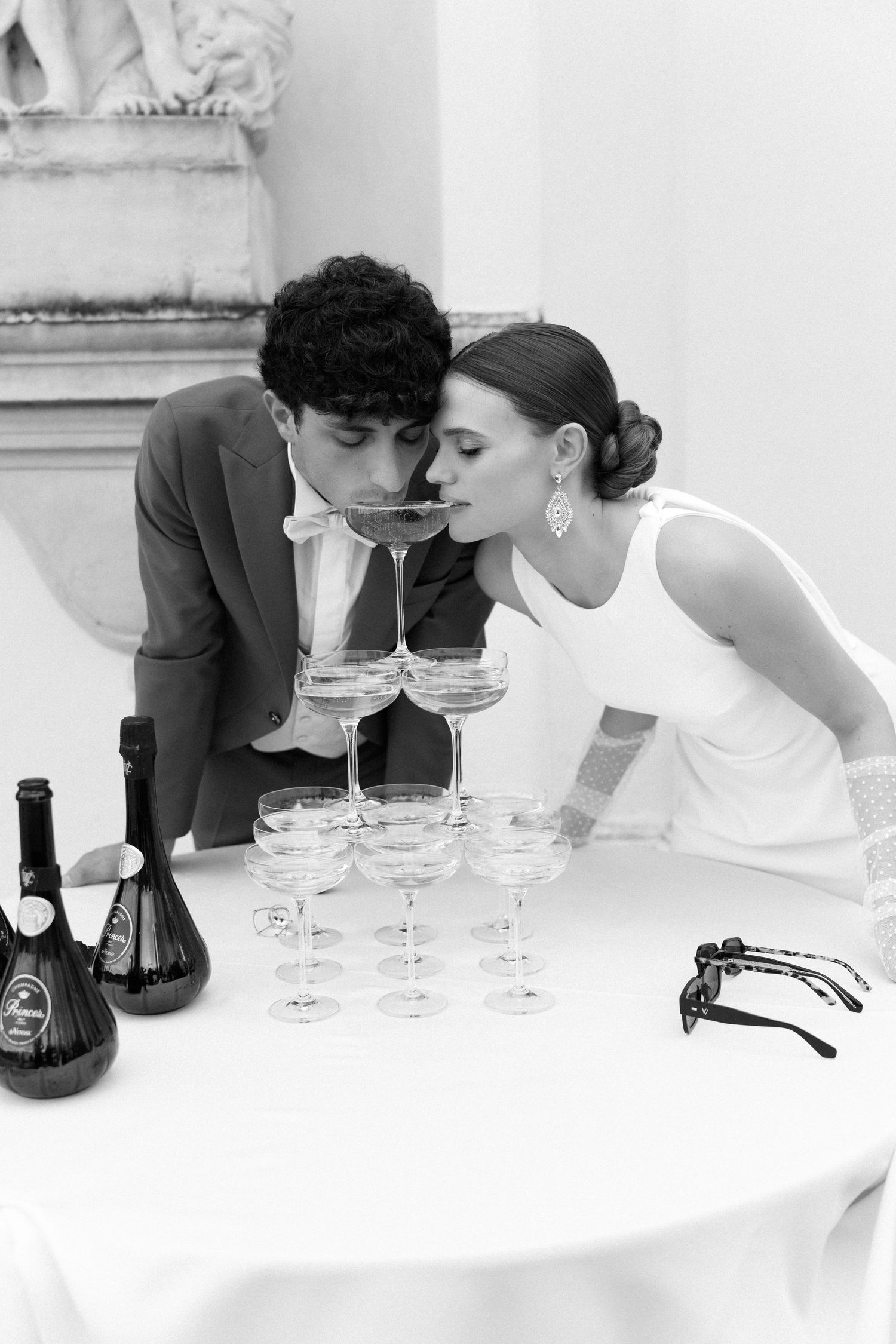A couple in formal attire drinks from a champagne tower at an elegant black and white celebration. Villa Mosconi Bertani