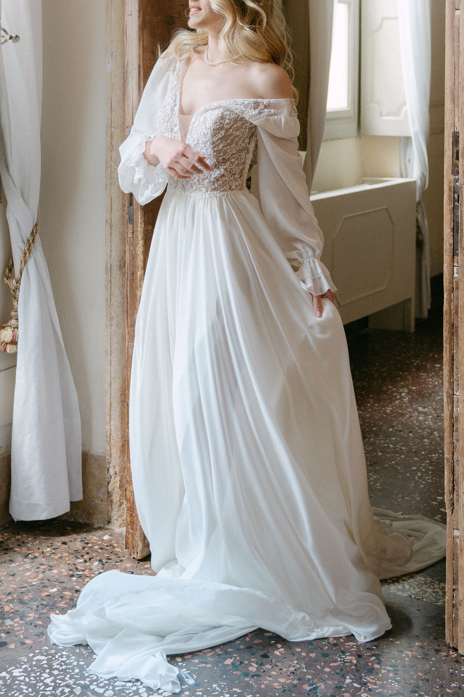 Ethereal off-shoulder wedding gown with billowing sheer sleeves, beaded bodice and flowing white chiffon skirt. Wedding Verona