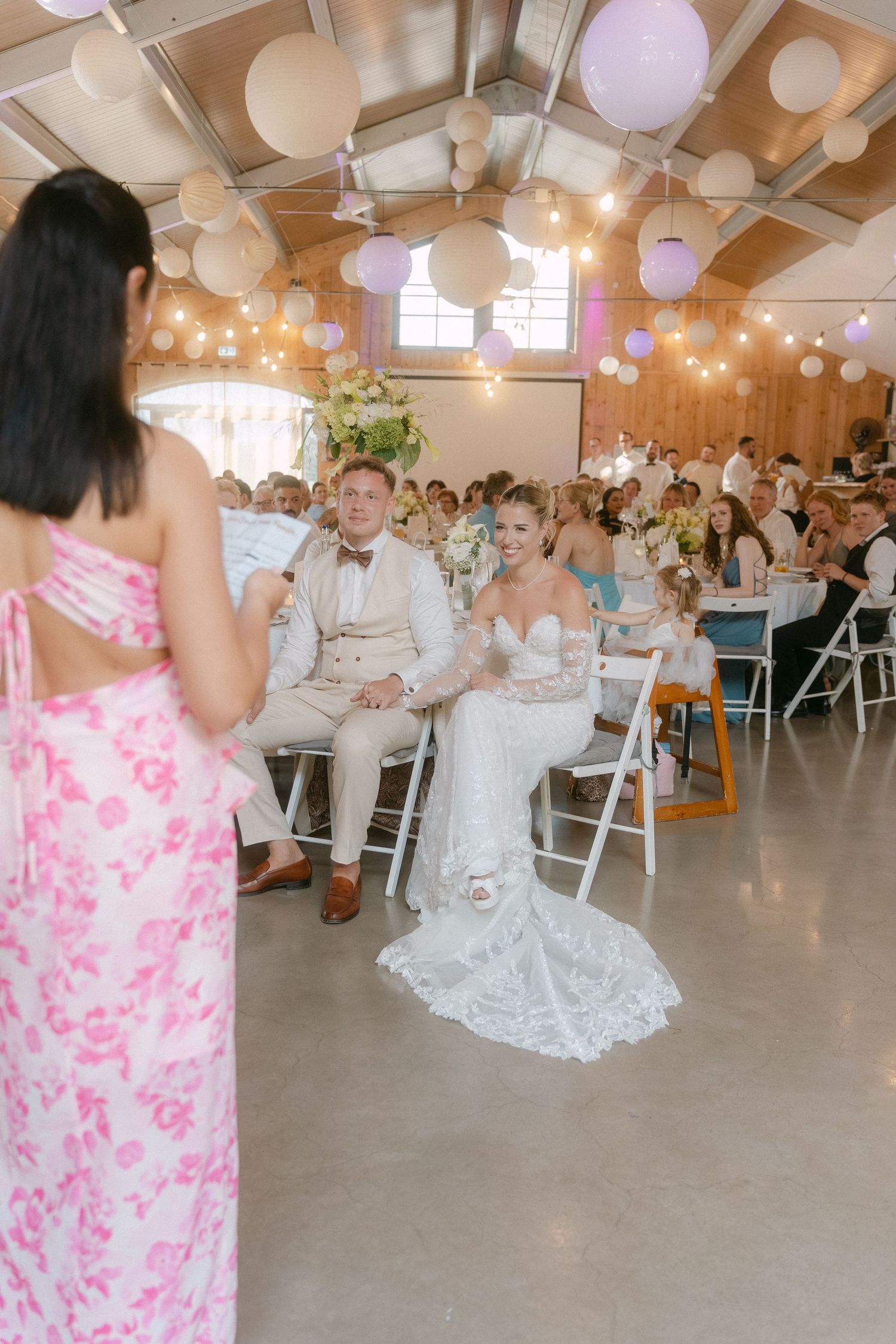 Wedding reception venue decorated with white paper lanterns and guests dancing on the dance floor during a celebration.