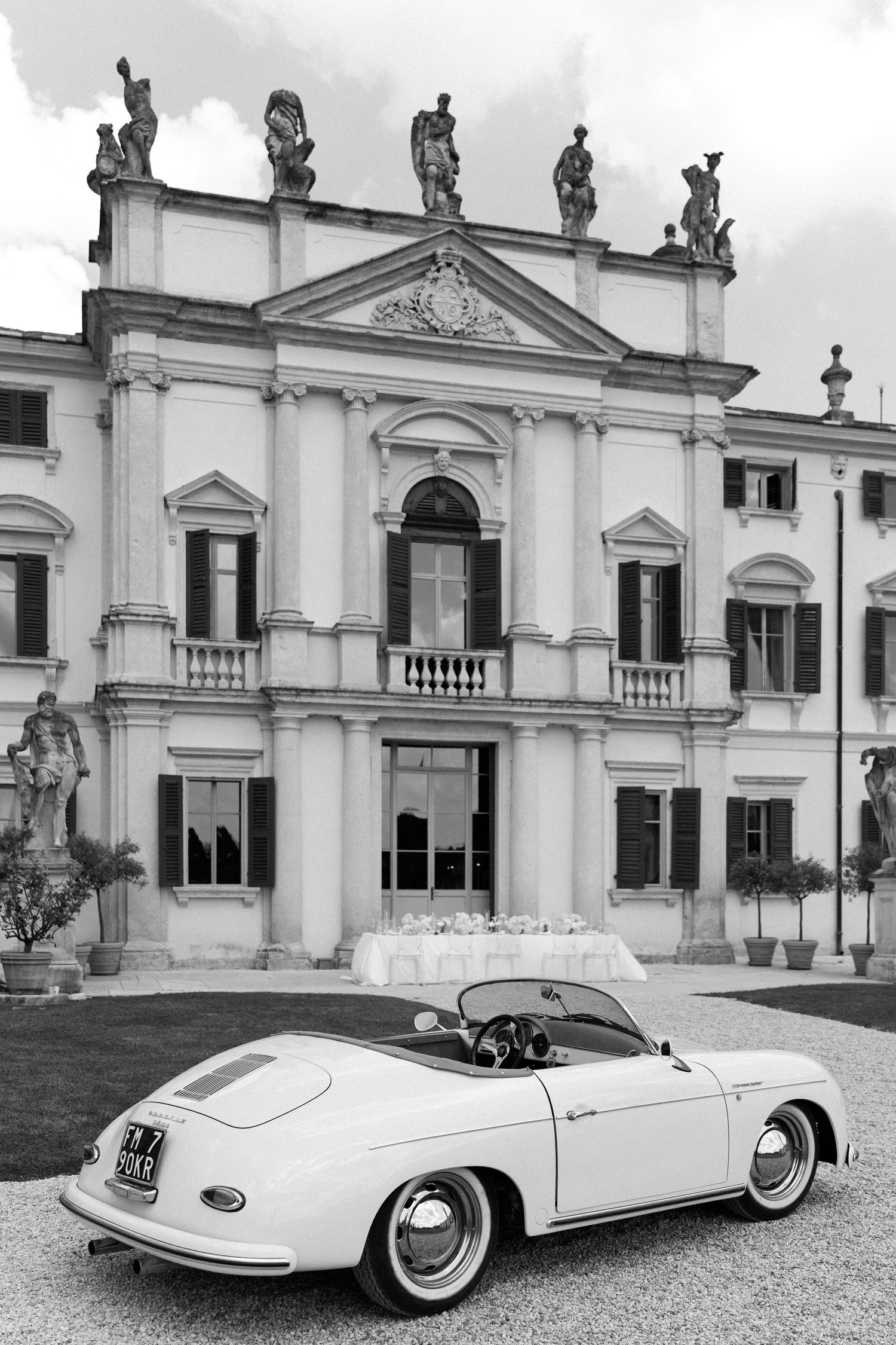 Classic white vintage convertible car parked in front of grand European villa.