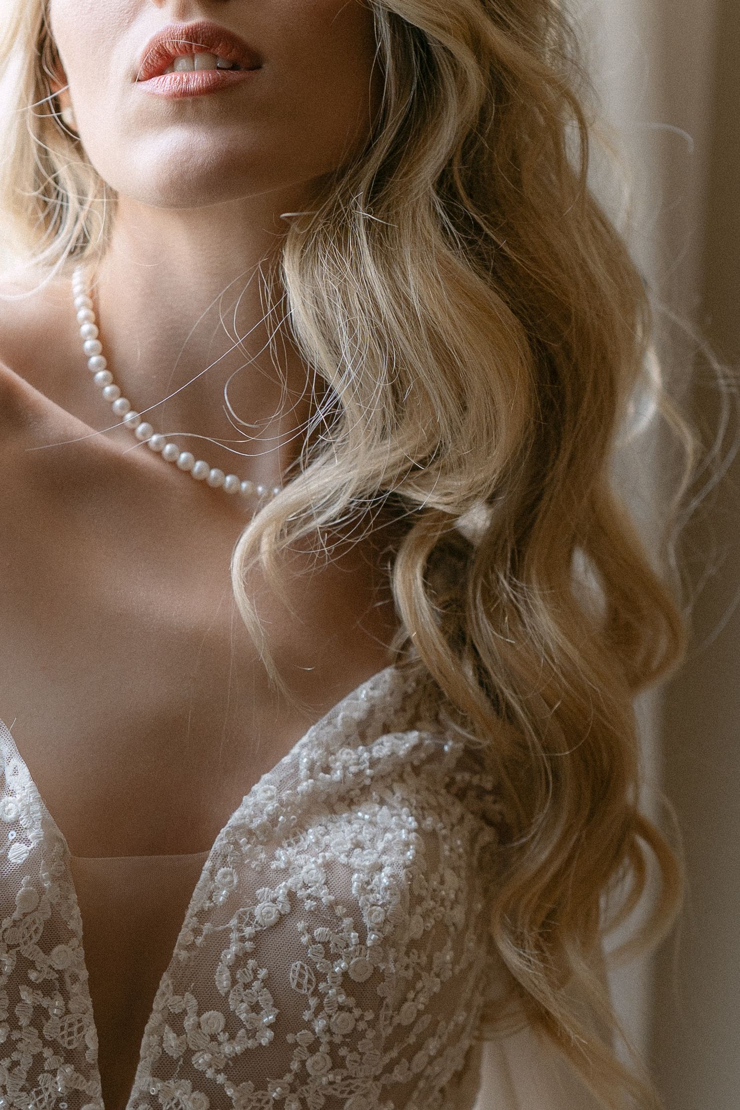 Elegant bridal portrait showing wavy blonde hair, pearl necklace and delicate lace wedding dress detail. Wedding Verona