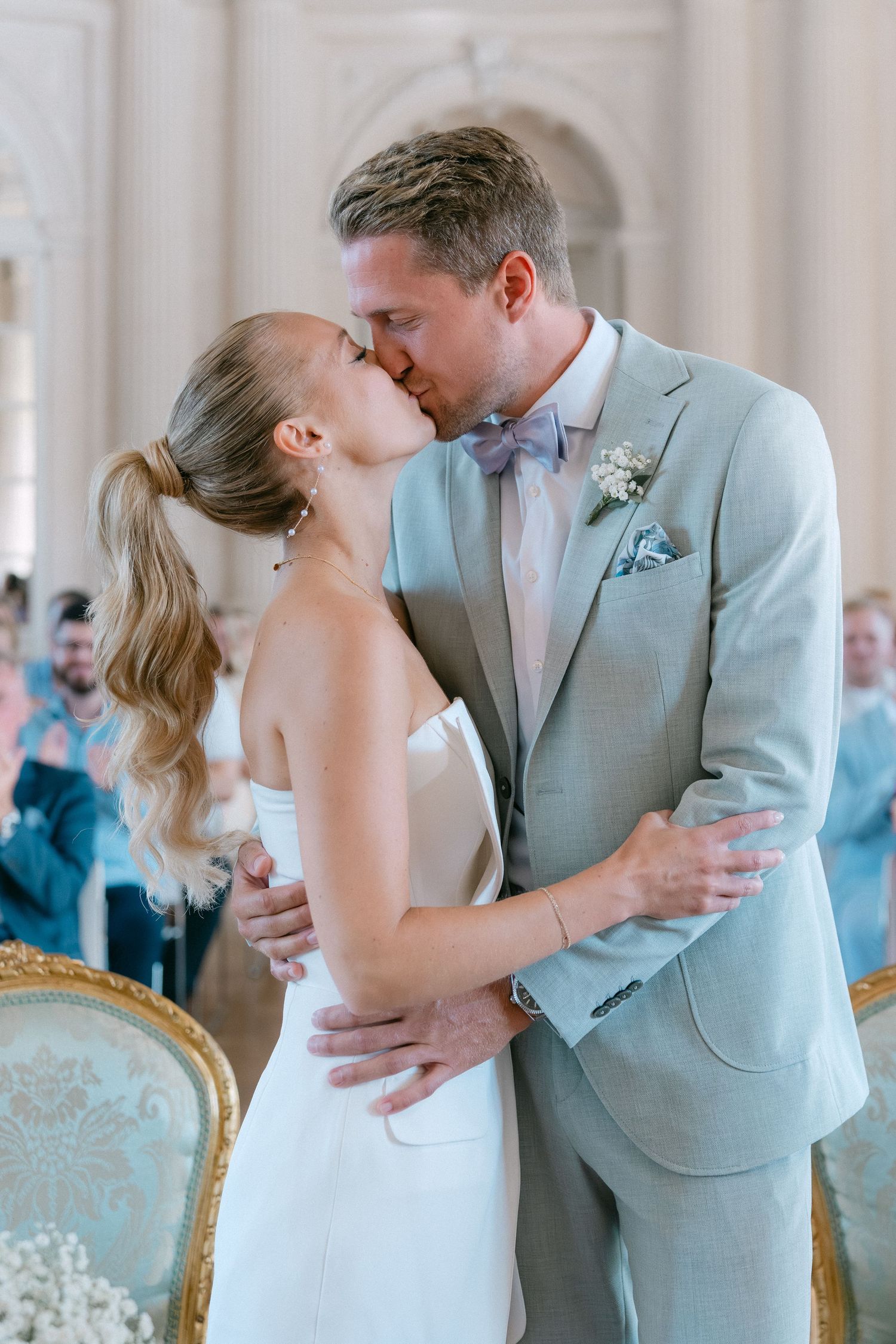 Newlyweds share a romantic kiss during their wedding ceremony in an elegant venue with mint green decor. Schloss Solitude