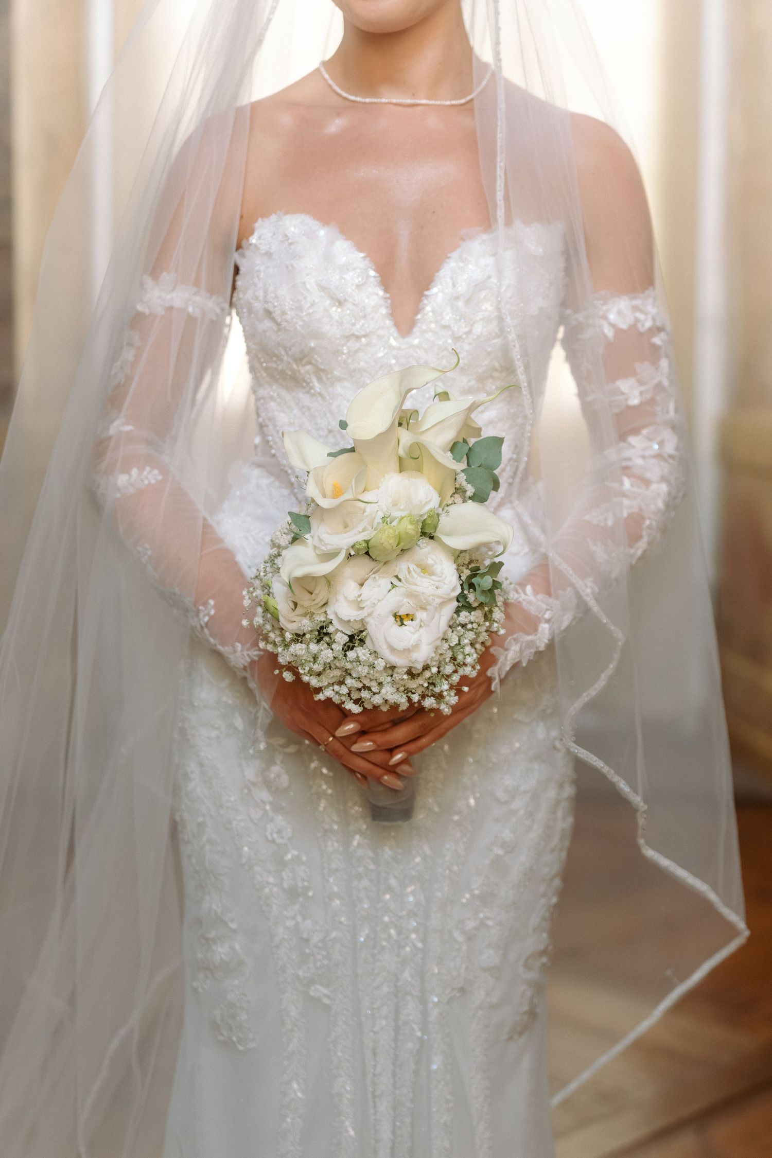 Close-up view of a bridal bouquet with white flowers and delicate lace details on a wedding dress. Schloss Ludwigsburg