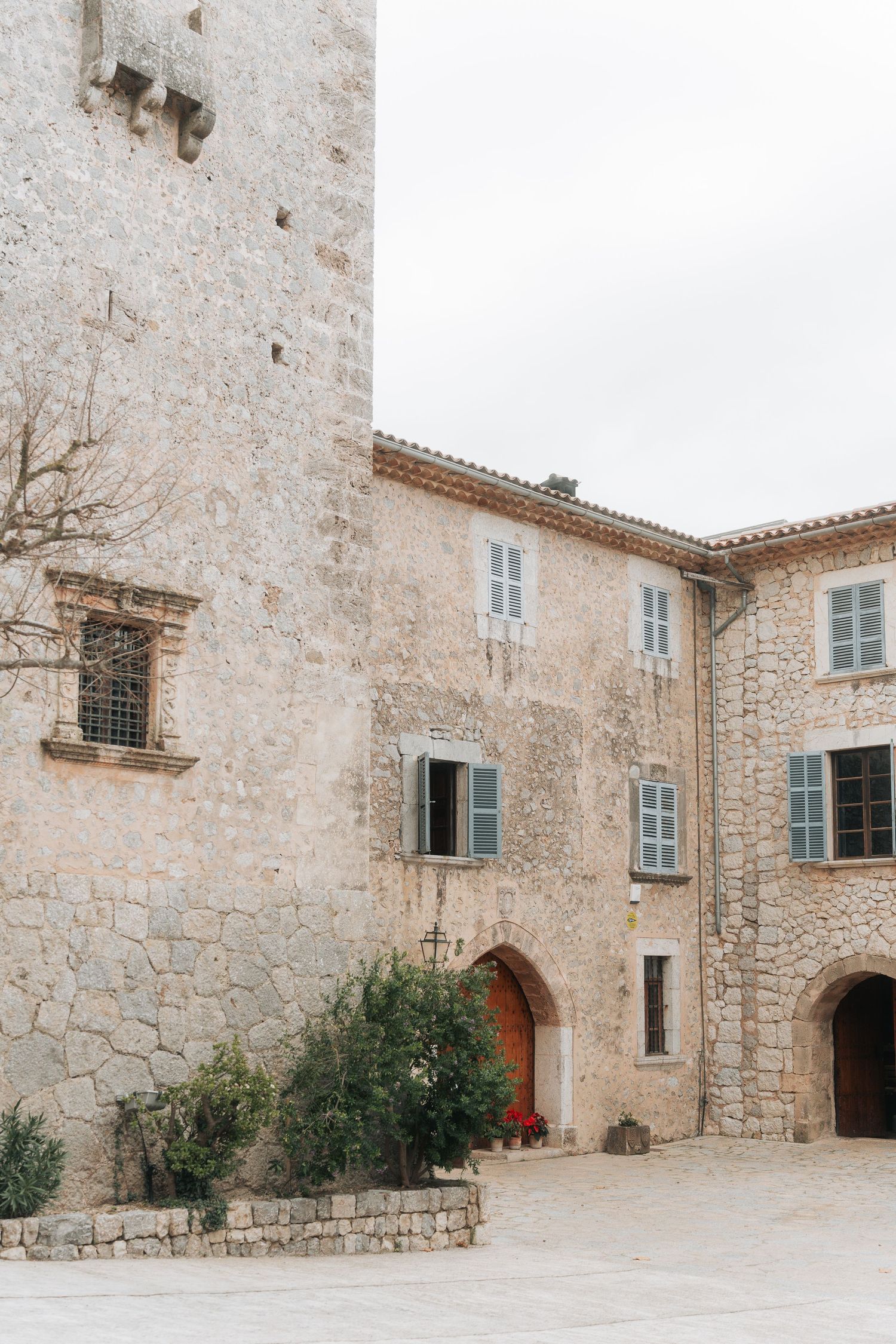 Historic stone villa exterior with pale walls and blue shuttered windows in Mediterranean architectural style.