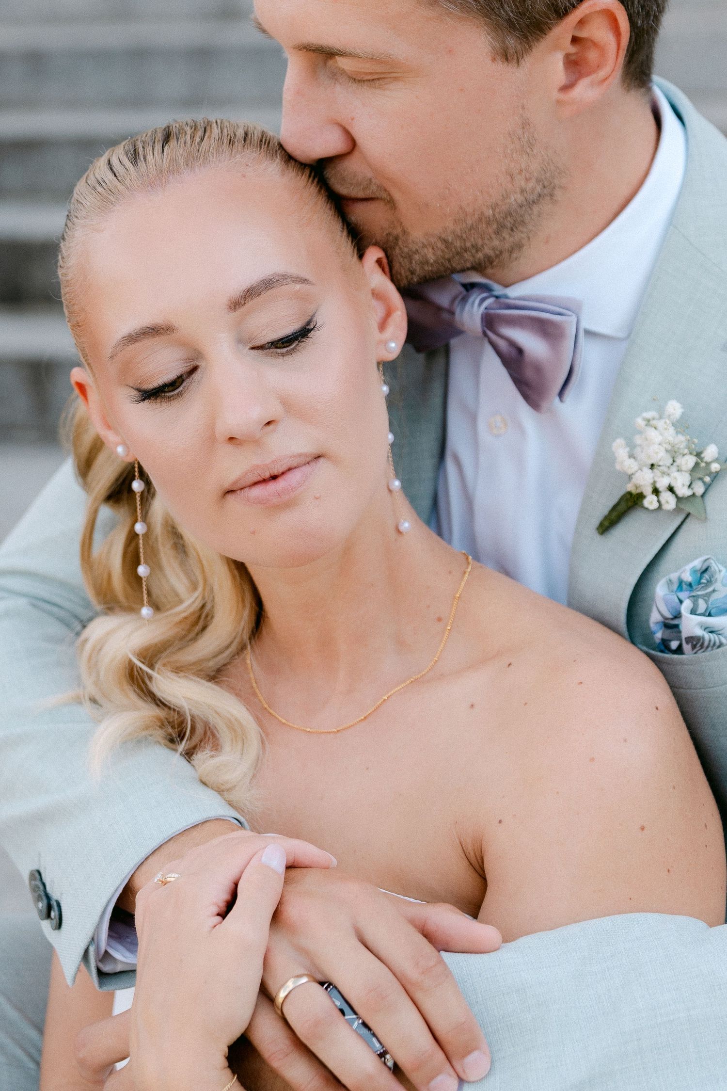 Romantic wedding couple embraces in tender moment against gray backdrop during intimate photo session. Schloss Solitude