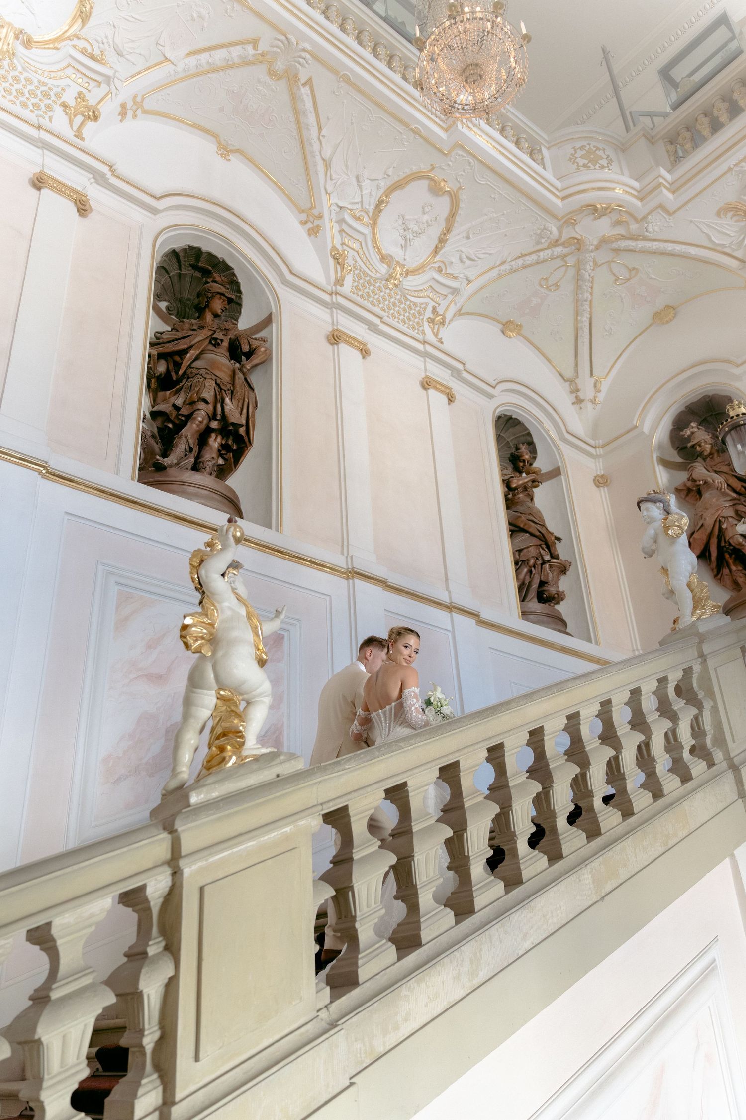 Ornate baroque staircase with white and gold details features decorative sculptures and intricate architectural elements.Schloss Ludwigsburg