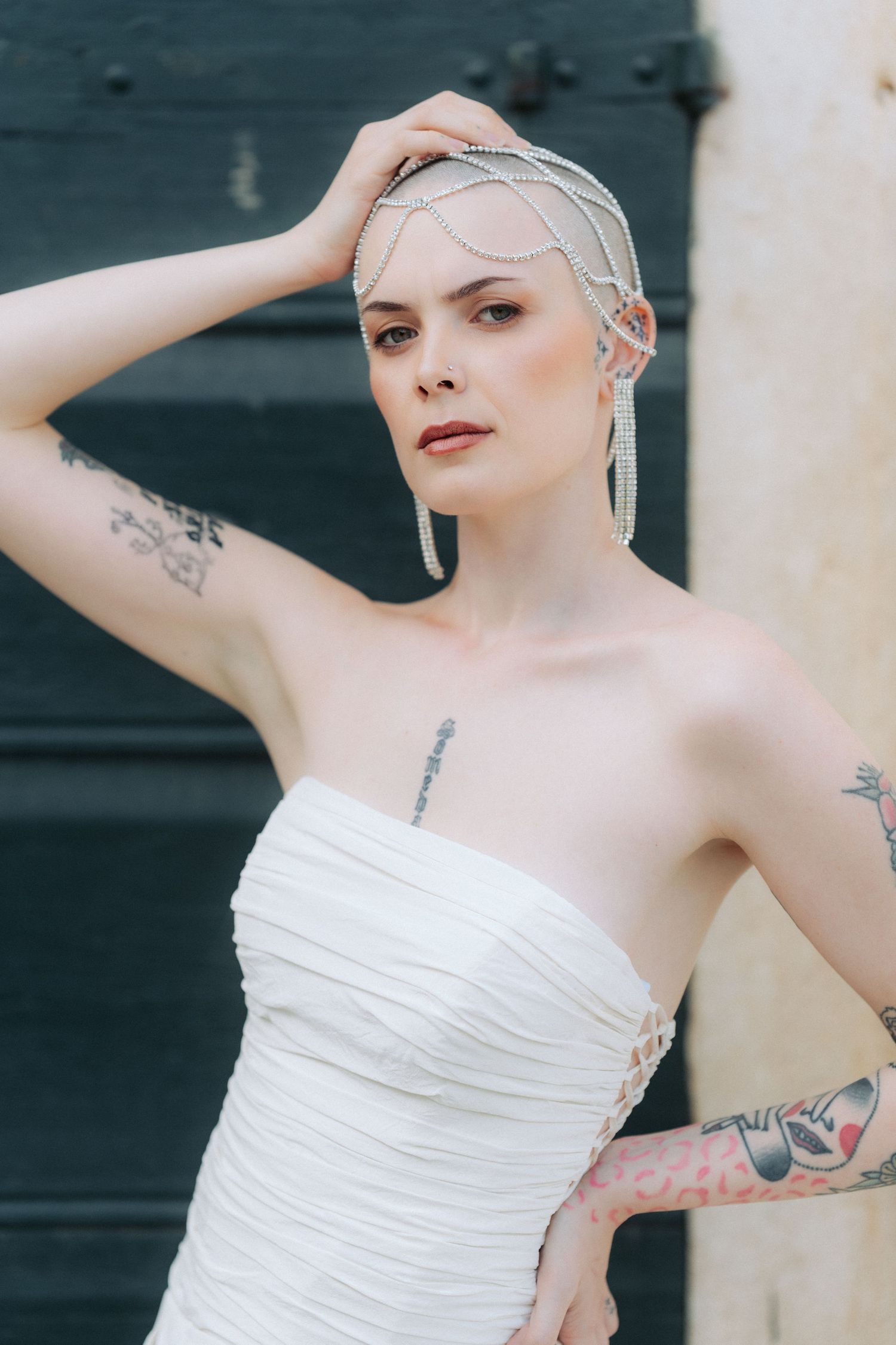 A figure in a white strapless dress poses gracefully with arms raised against a dark background.