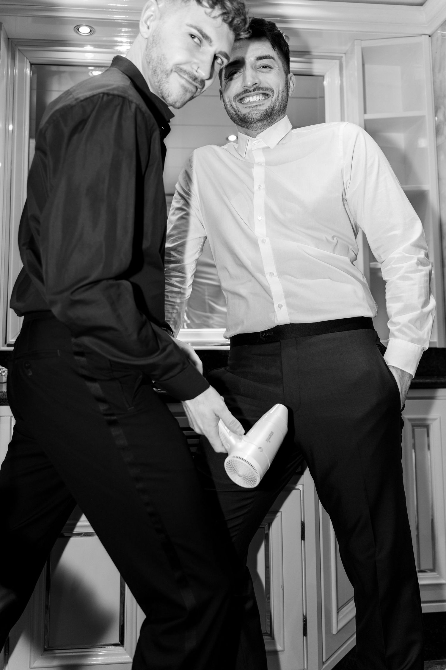Black and white photo of two men in formal attire posing together in an interior setting.