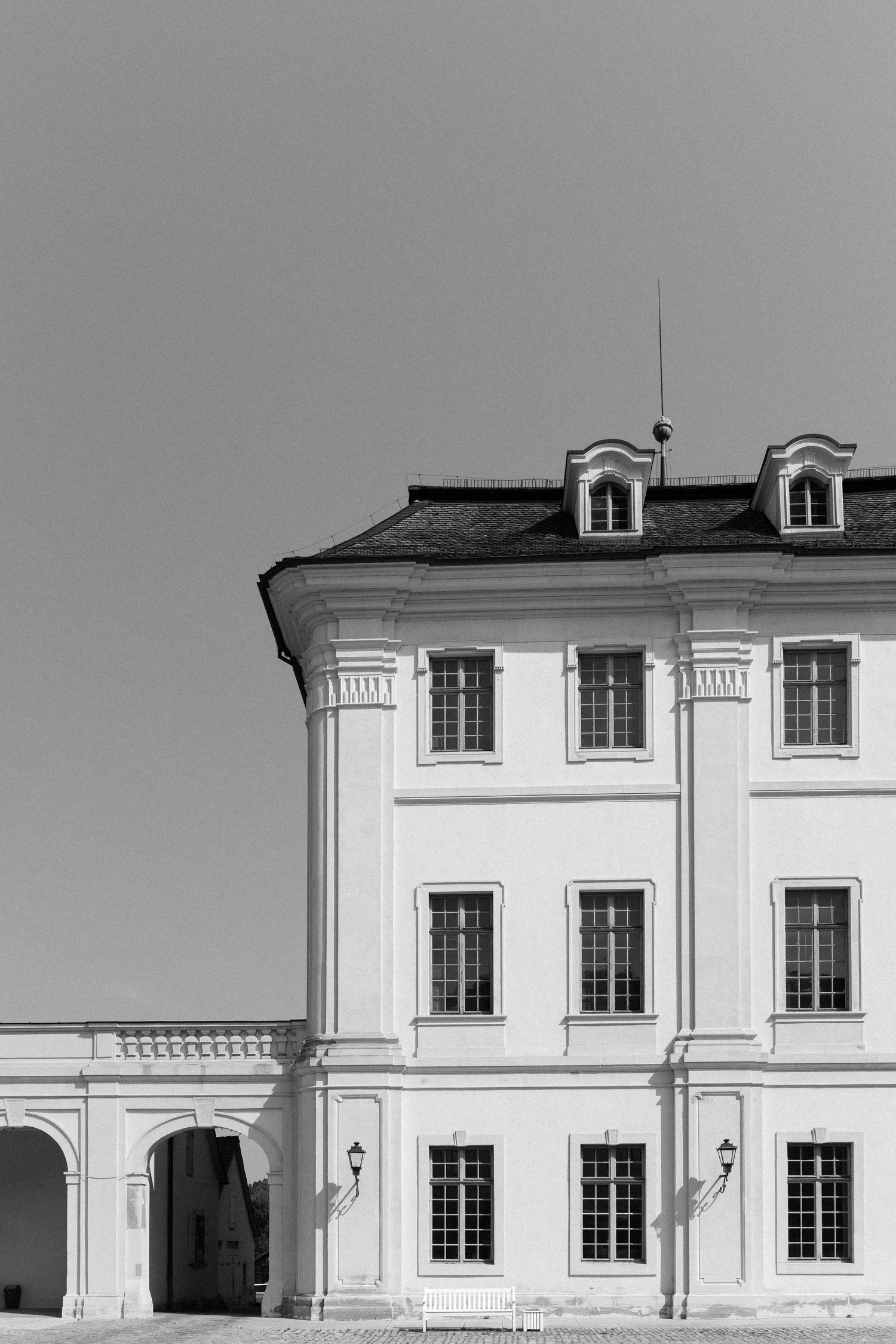 Black and white architectural detail of a white building facade with dormer windows and classical columns. Schloss Ludwigsburg