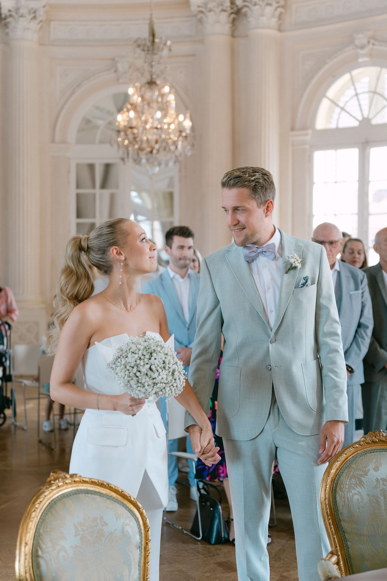 Wedding couple shares romantic moments in an elegant ballroom with crystal chandeliers and mint-colored attire. Schloss Solitude