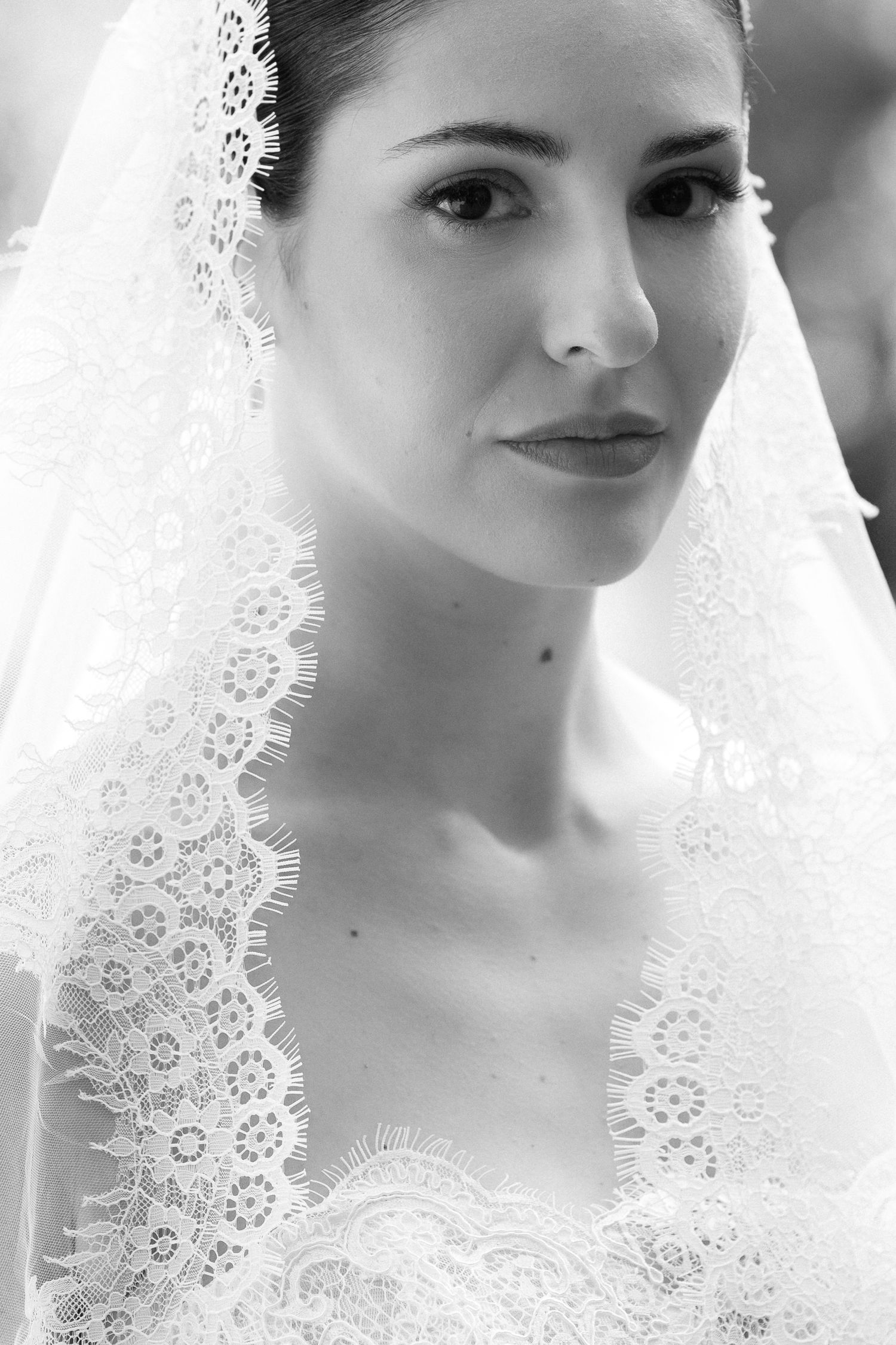 Black and white portrait of a beautiful bride wearing an elegant lace veil on her wedding day.