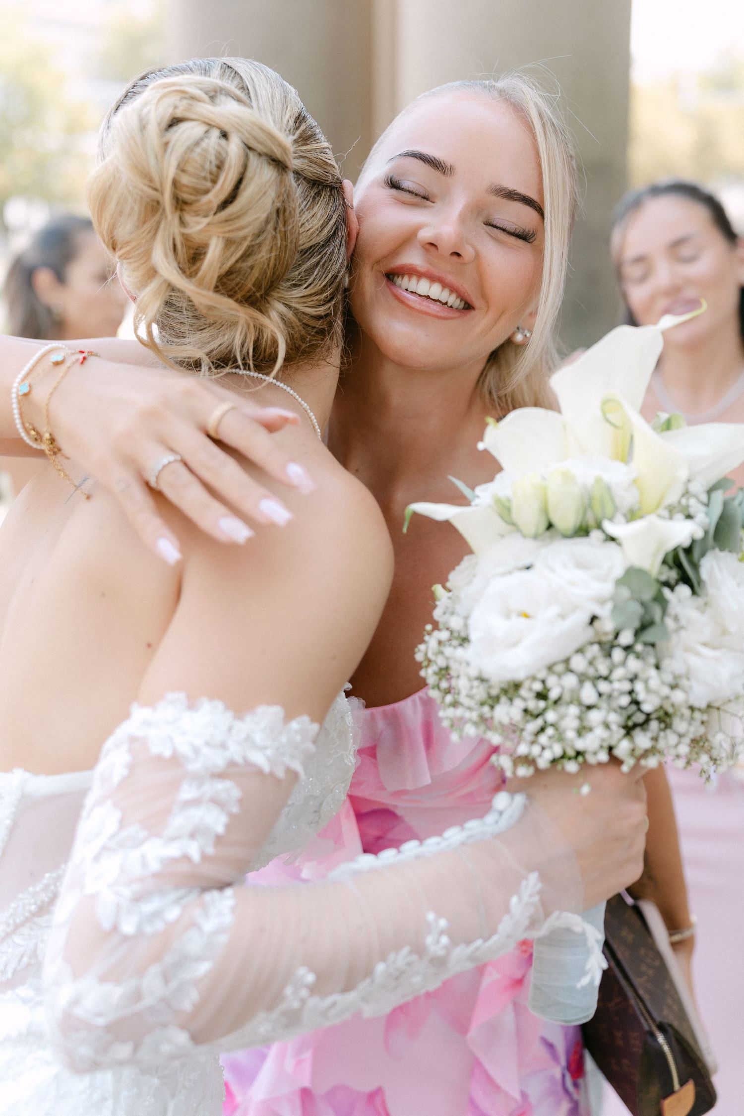 Two people share a joyful embrace at a wedding celebration with white flowers and baby's breath bouquet in view.