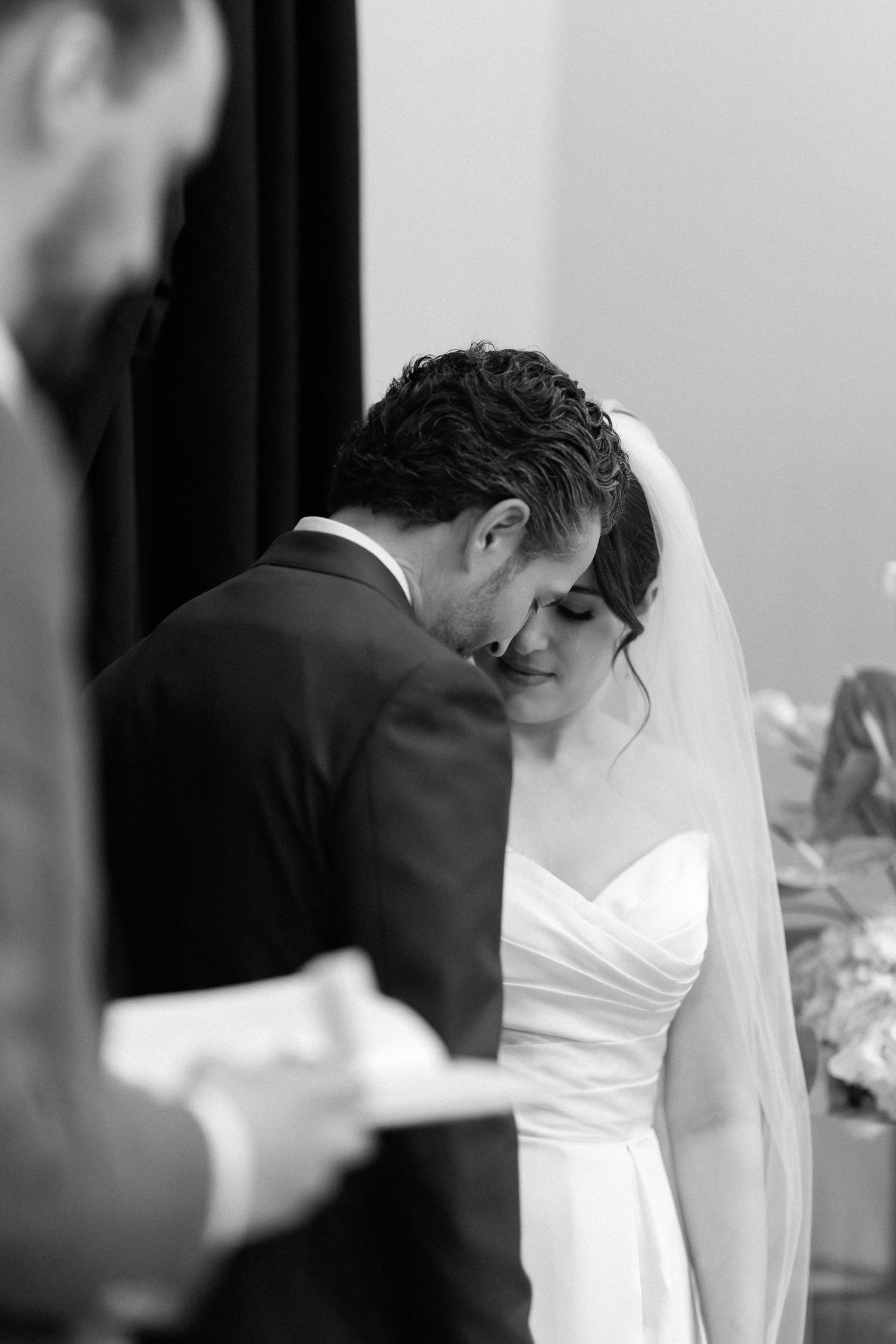Black and white photo of a bride and groom sharing an intimate moment during their wedding ceremony.