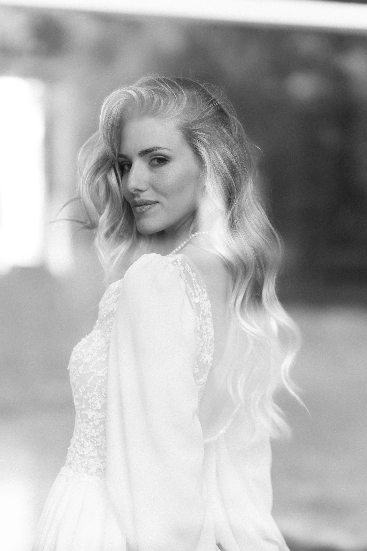 Black and white portrait of a bride with flowing blonde wavy hair wearing a lace wedding dress in soft focus. Wedding Verona