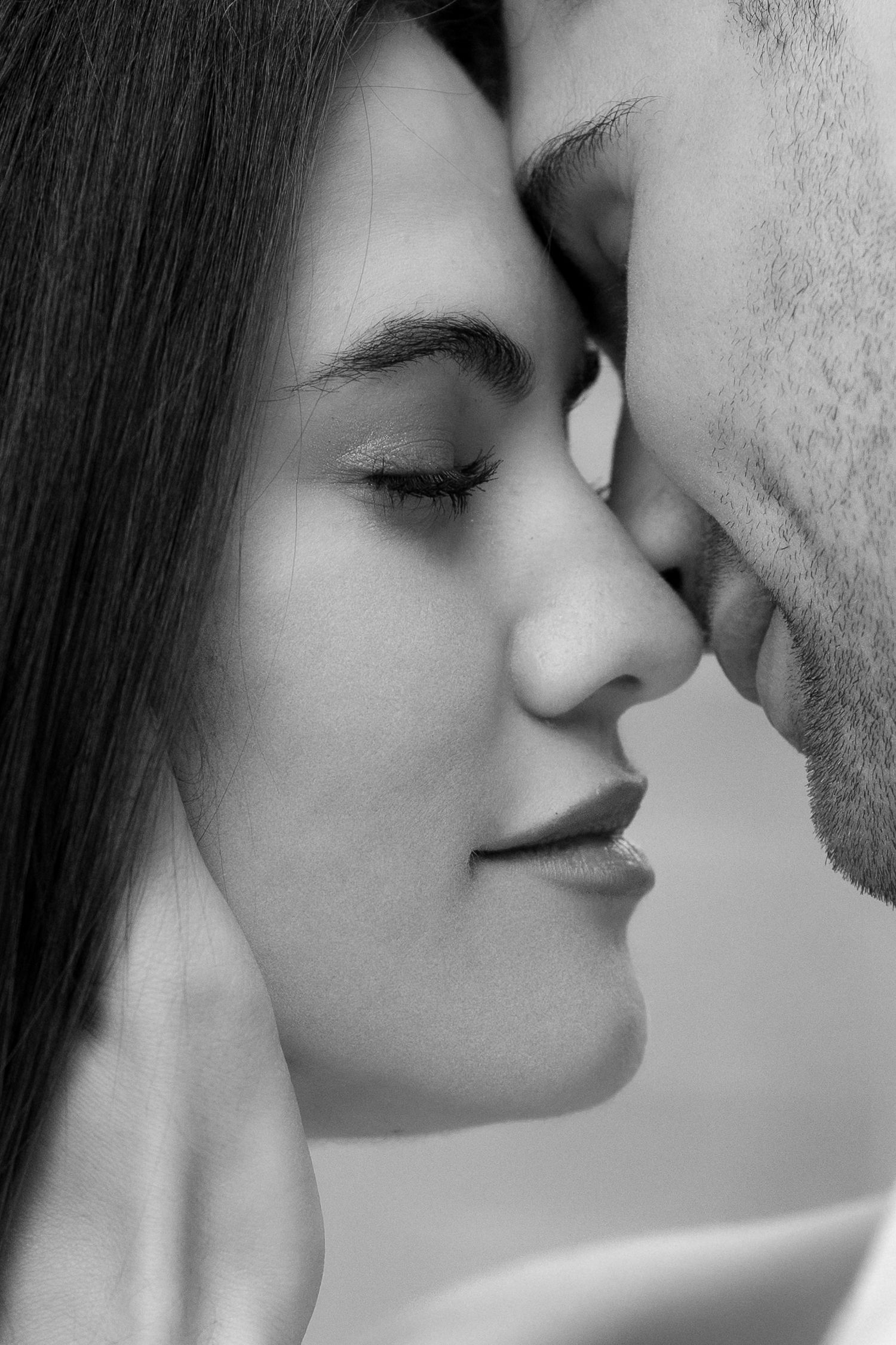 A romantic black and white close-up of two people about to share an intimate kiss.