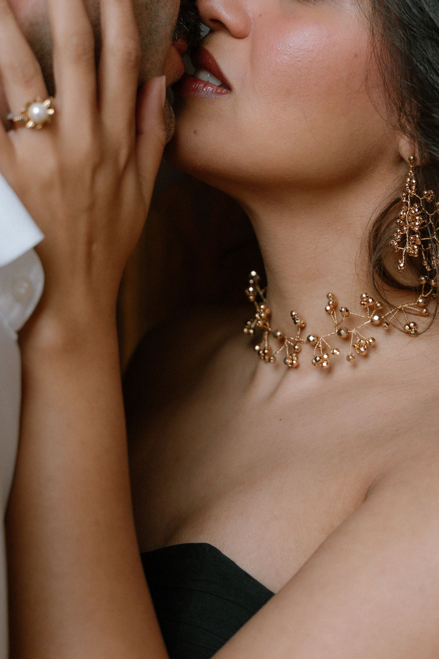 Woman wearing elegant gold branch necklace and matching earrings with pearl ring, close-up romantic portrait.