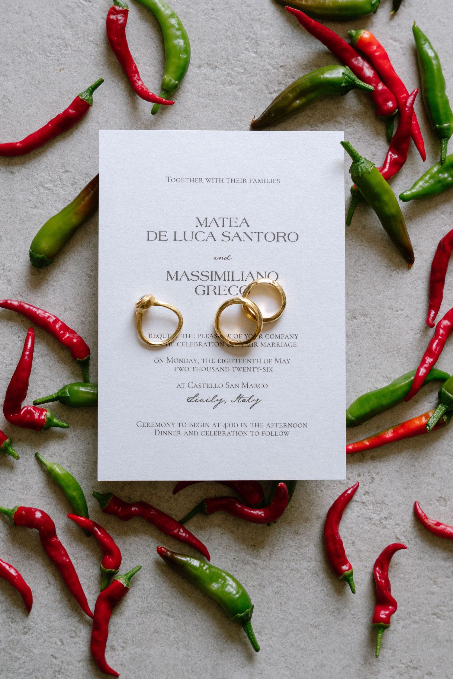 Wedding invitation for Matea De Luca Santoro and Massimiliano Greco with gold rings, surrounded by red and green chili peppers.