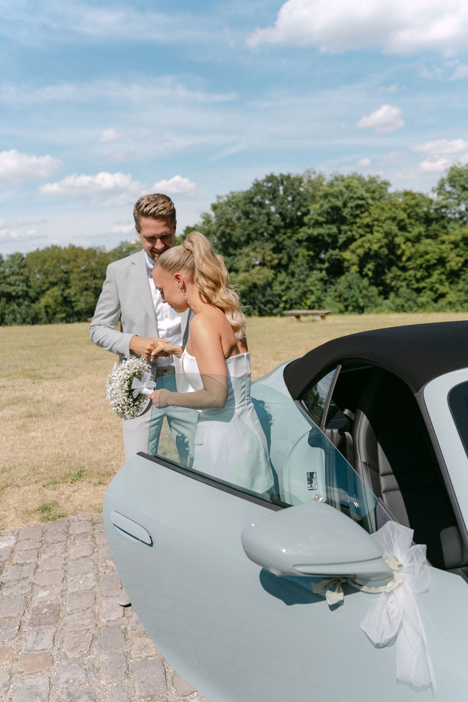 A romantic sequence of a couple sharing a kiss through a vintage car window in a sunny field on their wedding day. Schloss Solitude