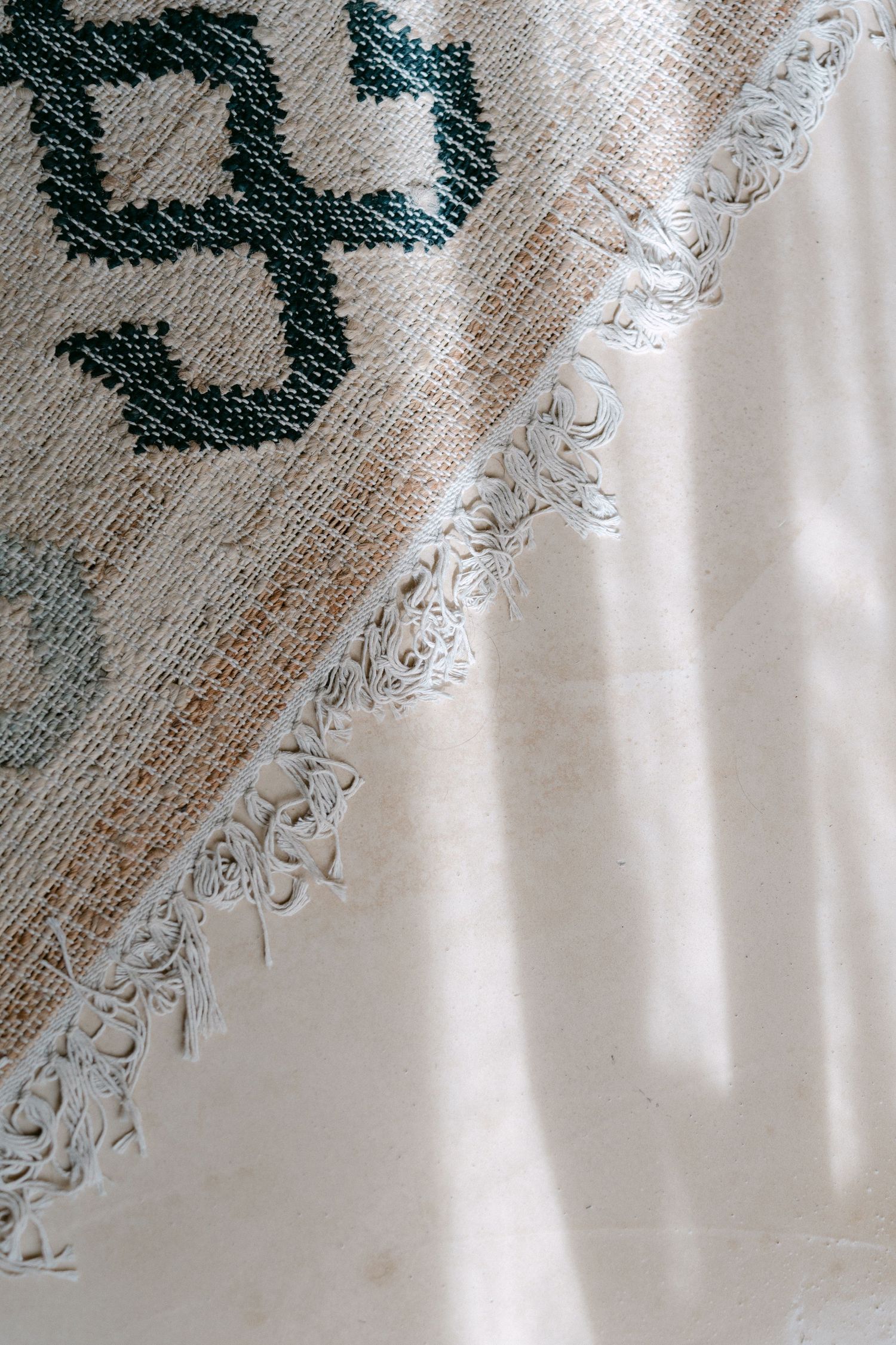 Close-up detail of white textured fabric with an embroidered dark green pattern.