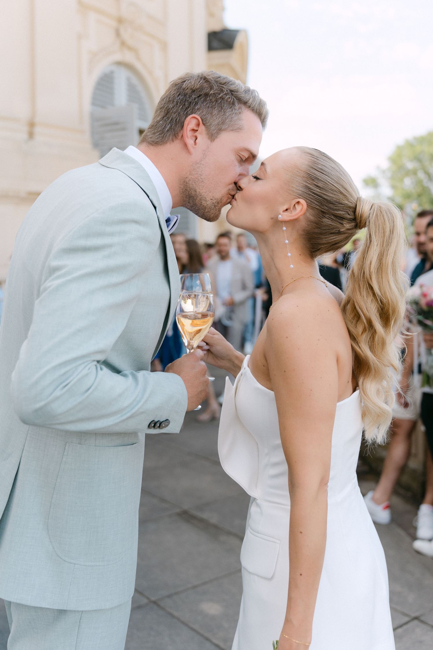 A couple shares a romantic kiss sequence during their wedding celebration outdoors. Schloss Solitude