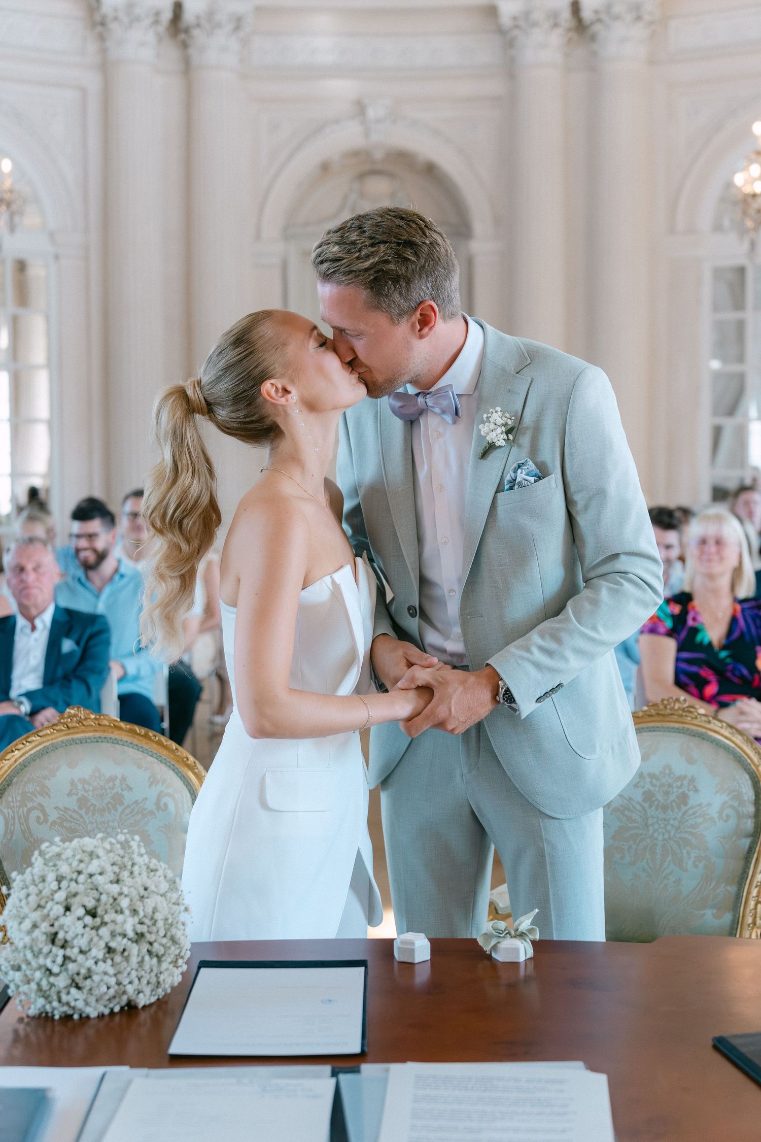 Romantic wedding ceremony moment showing couple signing marriage documents in an elegant room with ornate decor. Schloss Solitude