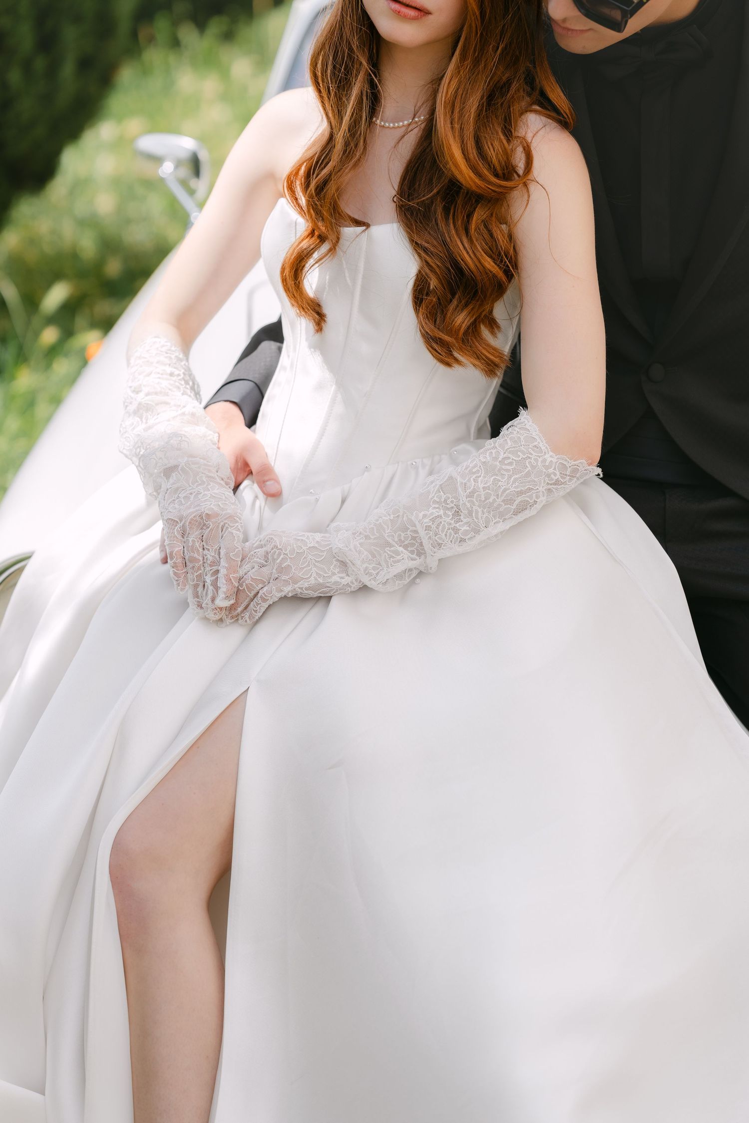 Close-up detail of an elegant white wedding dress with lace sleeves and flowing skirt, showing delicate fabric texture.
