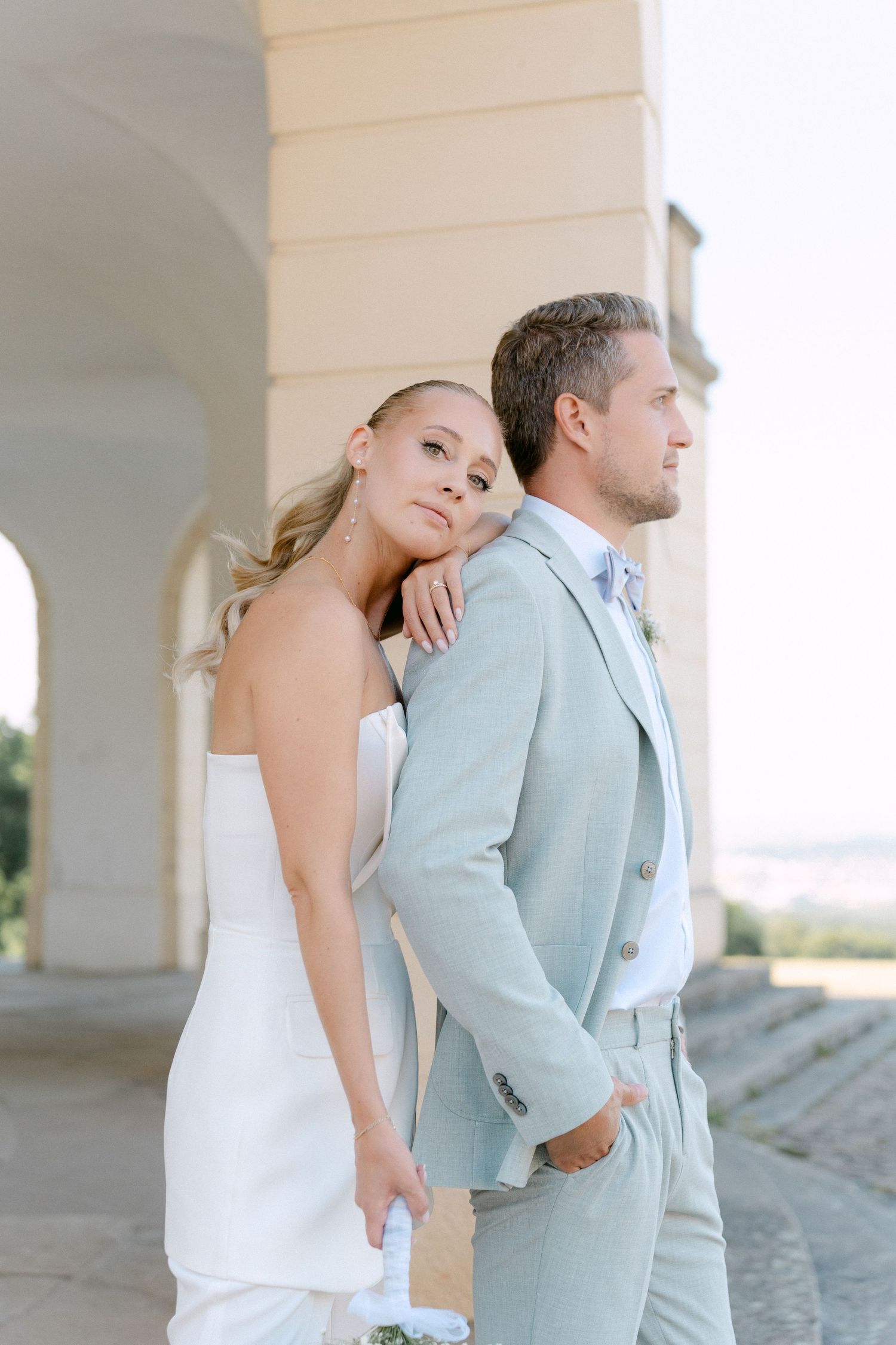 Bride and groom share an intimate moment in a light and airy outdoor setting with white columns. Schloss Solitude