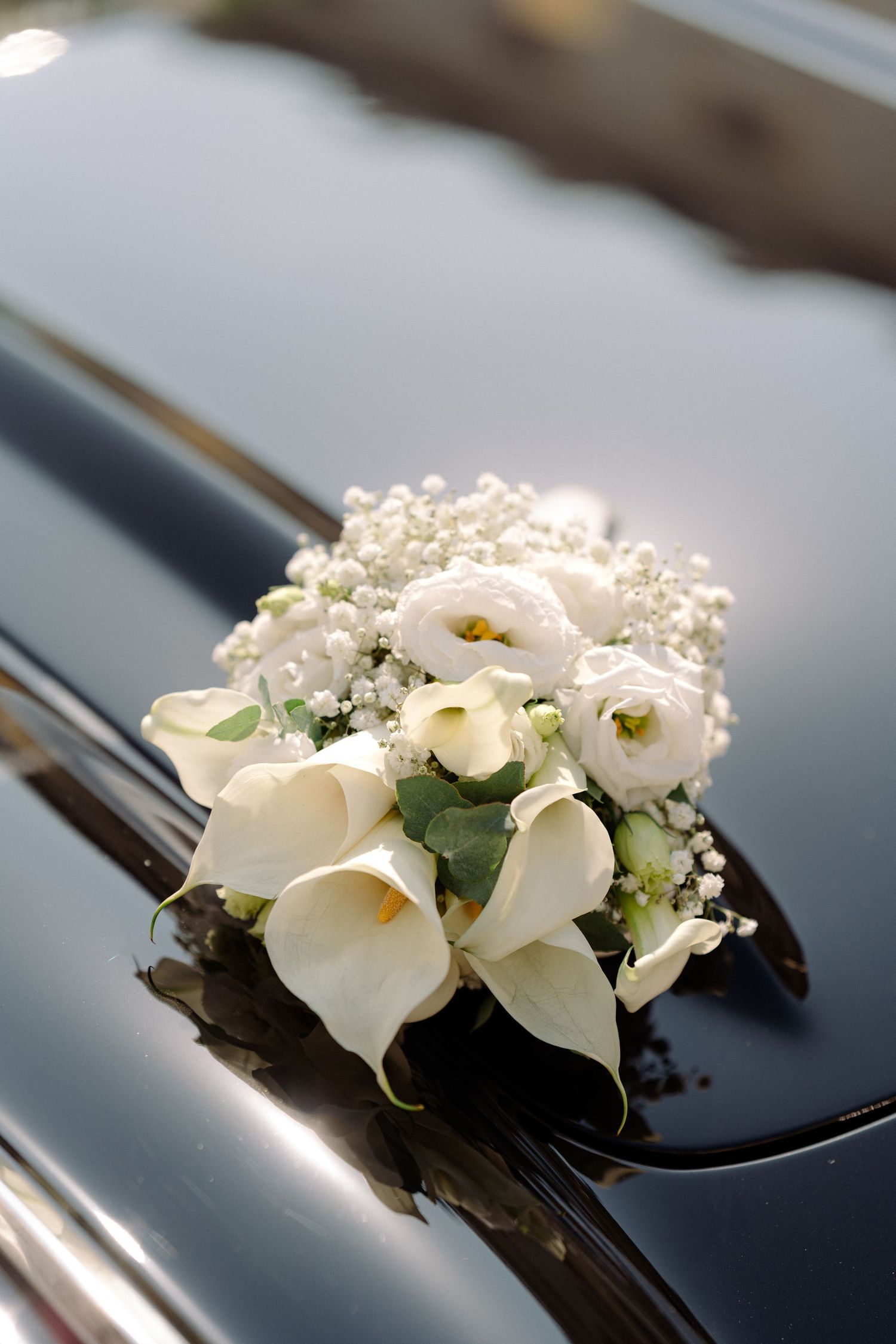 White calla lilies and baby's breath flowers arranged as elegant wedding car decorations on a black surface. Schloss Ludwigsburg