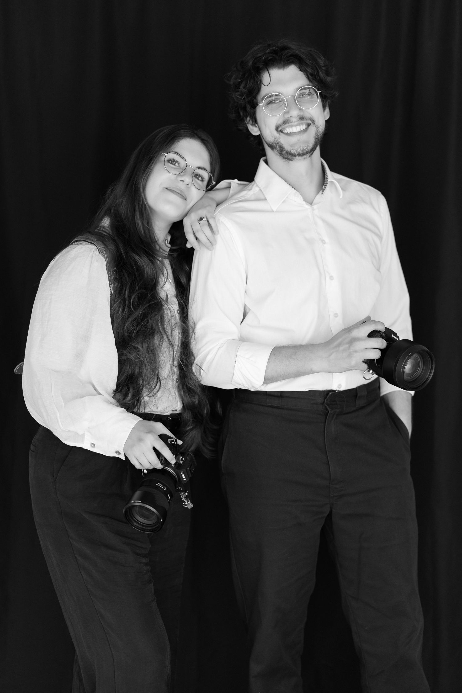 Professional photographers pose together in contrasting black and white clothing.