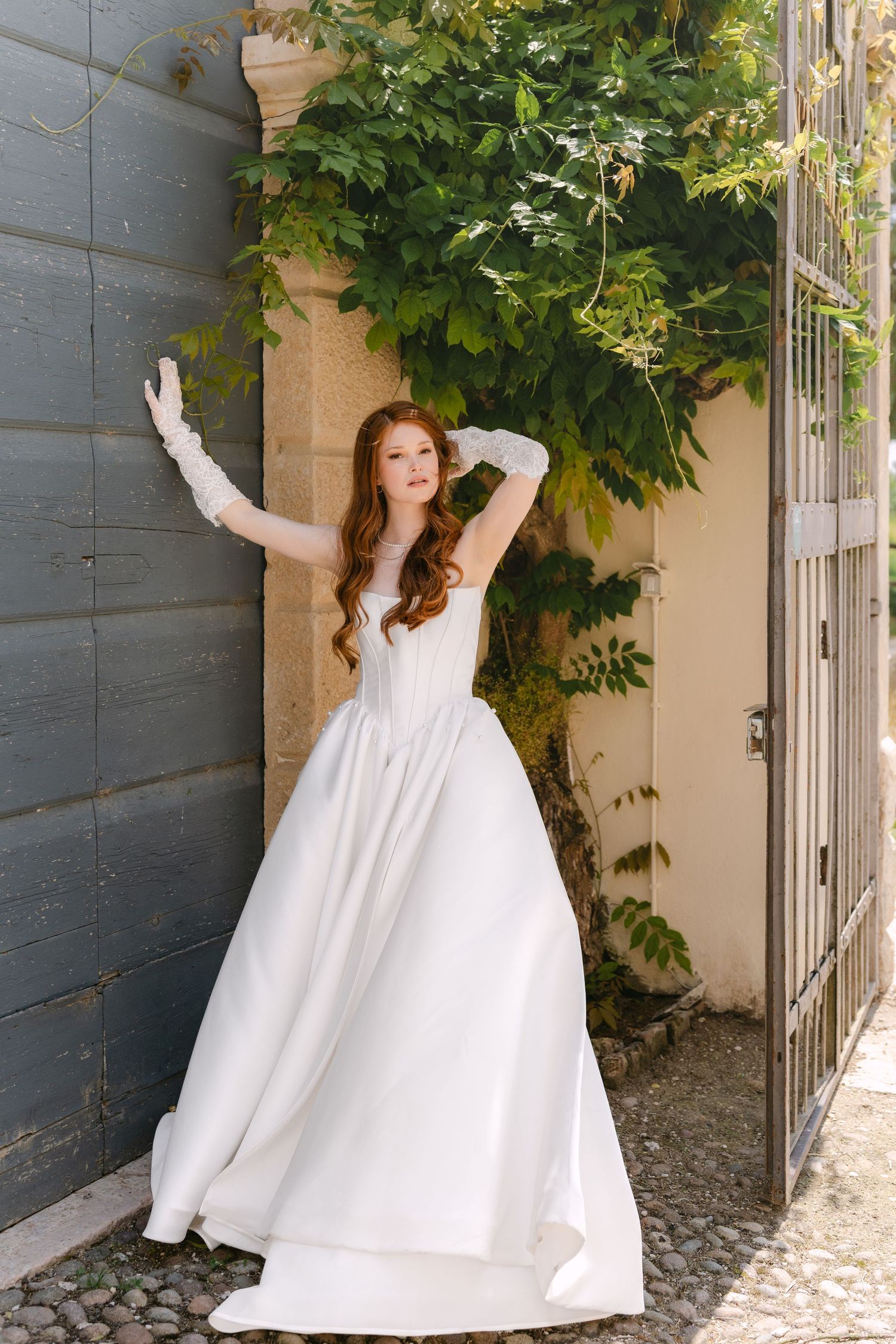 A sequence of photos showing a person in a flowing white dress posing playfully against a gray wall with green foliage.