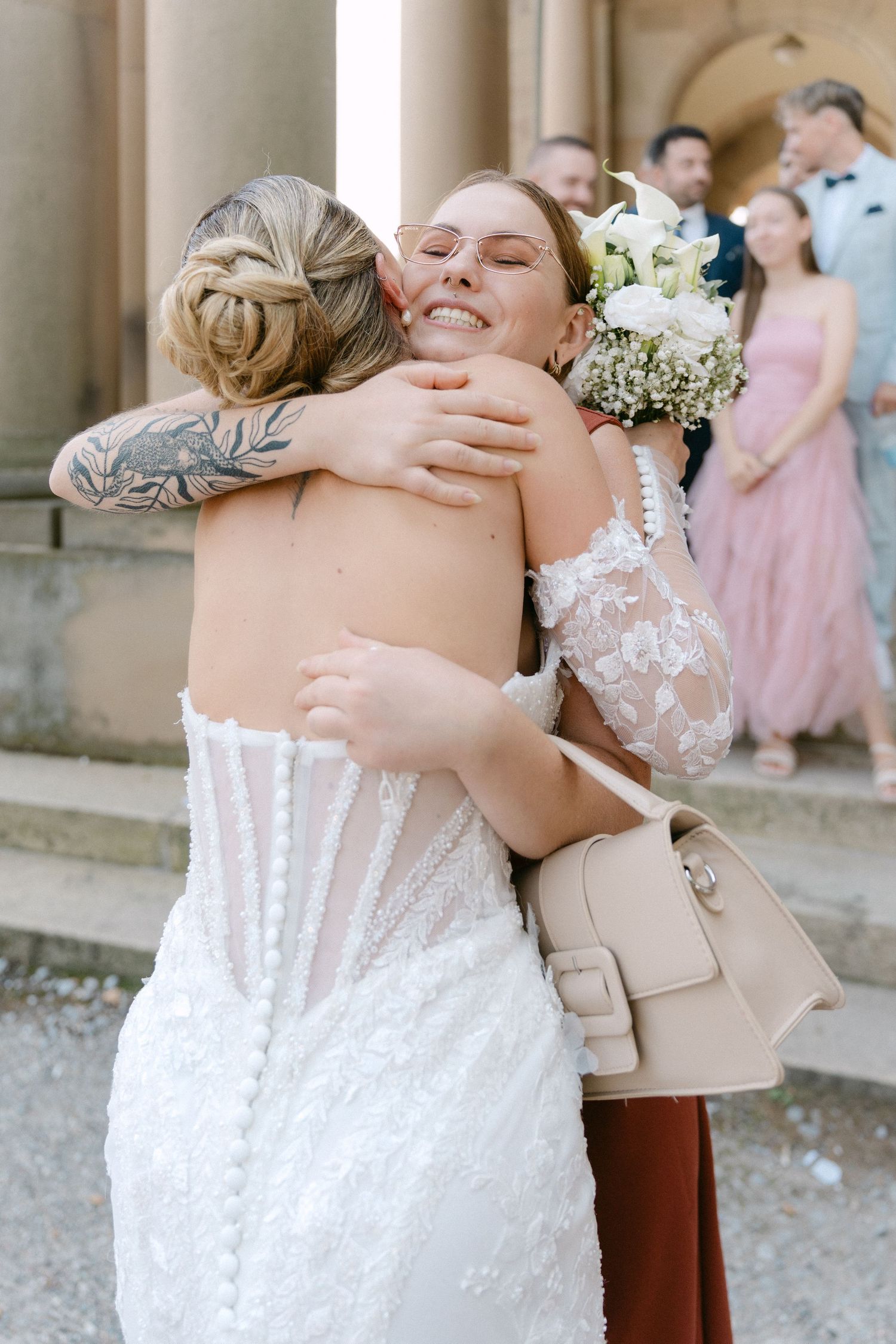 Emotional wedding moments captured with guests in pastel attire sharing embraces.