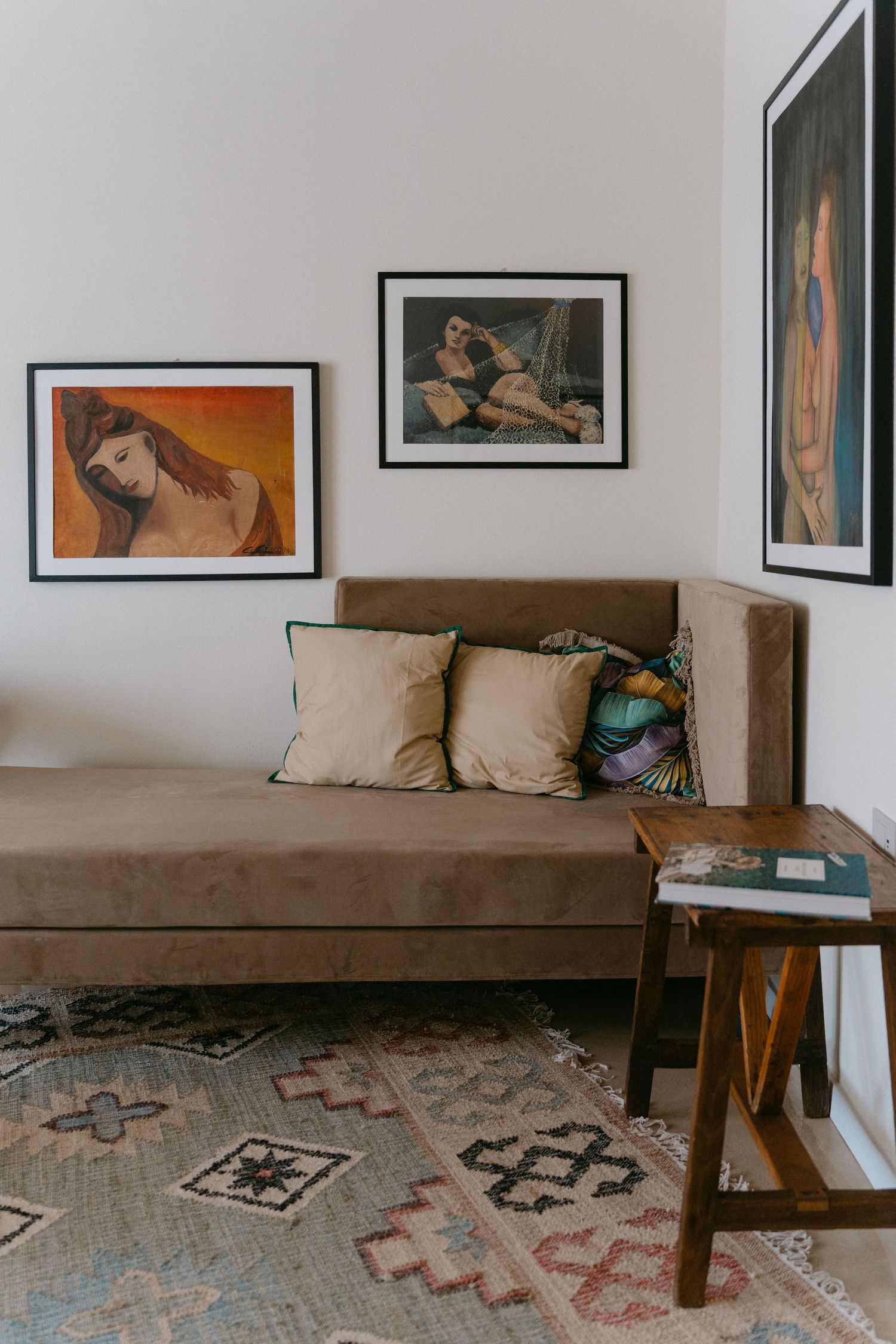 Modern living room with wooden bench seating and framed artwork on white walls.