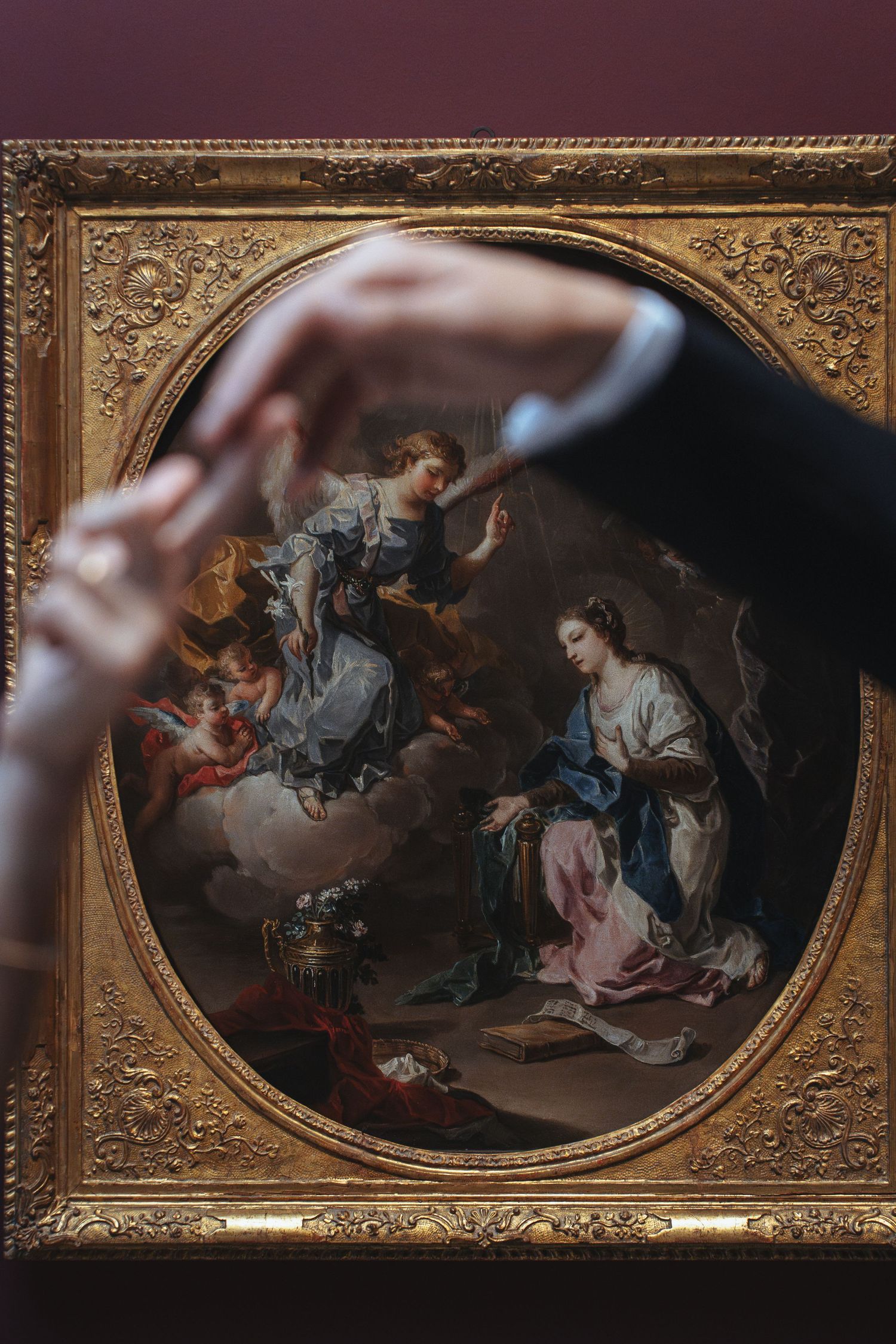 A classical religious painting in an ornate gold frame depicts the Annunciation scene with divine and earthly figures.