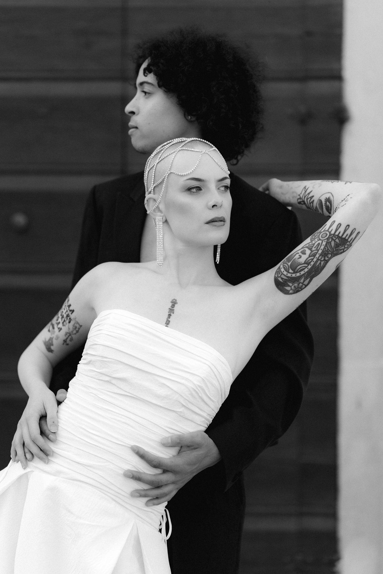 A series of black and white photos showing a person in a white dress with tattoos striking dramatic poses.