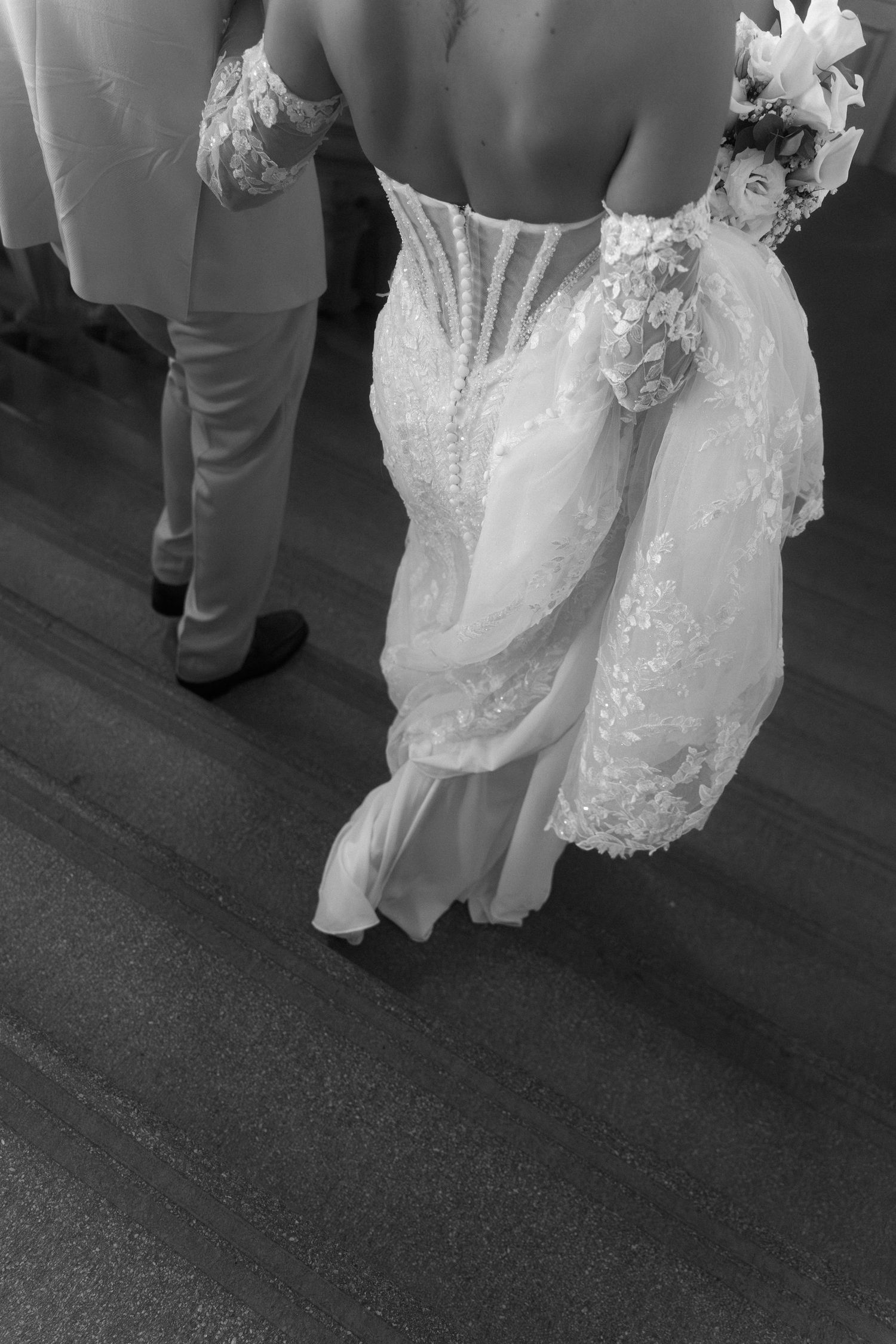 Black and white photo showing the hem of a lace wedding dress and formal shoes on a dance floor. Schloss Ludwigsburg