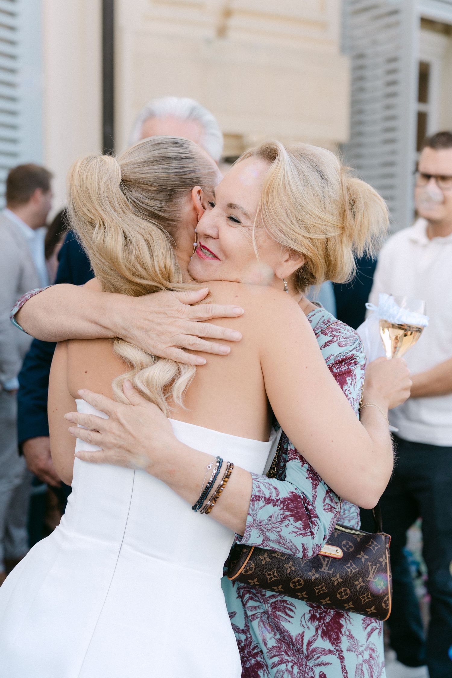 Two people share a warm embrace at what appears to be a wedding celebration outdoors. Schloss Solitude