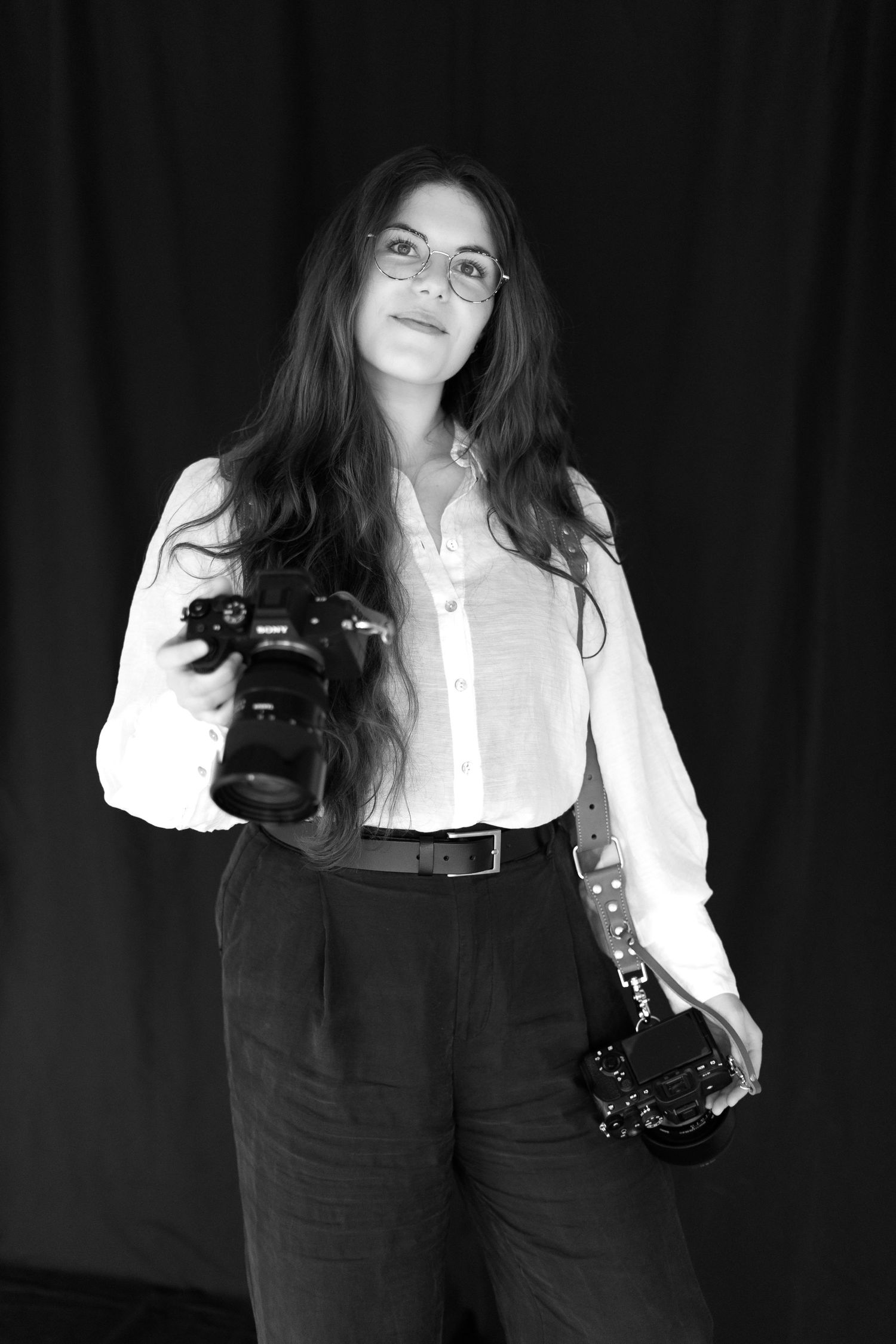 Artistic black and white portrait of someone in white shirt holding a vintage camera.