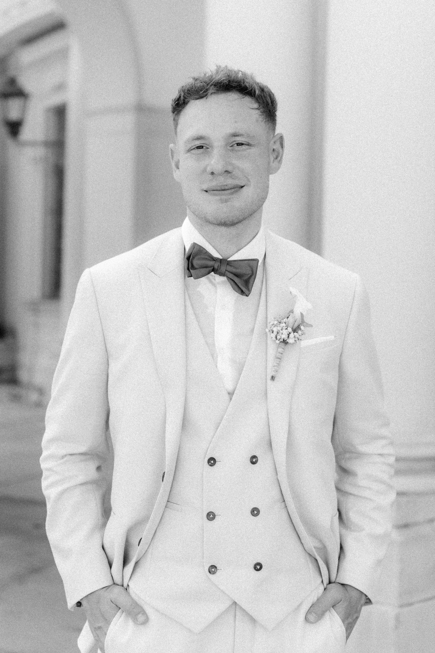 A series of black and white wedding photos showing someone wearing a white tuxedo with a bowtie in different poses. Schloss Ludwigsburg