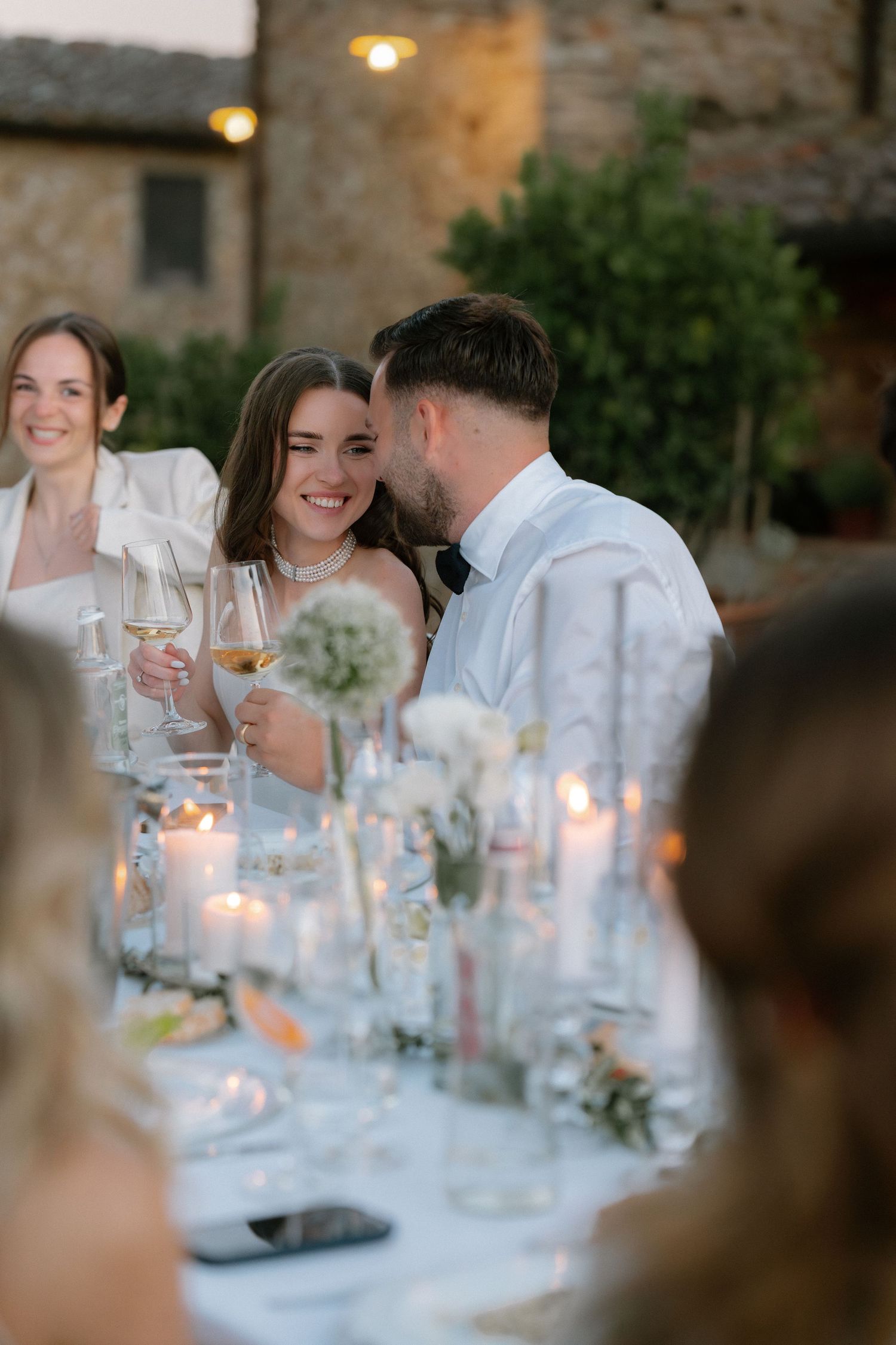 Bride and groom share a romantic moment at an elegant candlelit outdoor wedding reception in Tuscany.